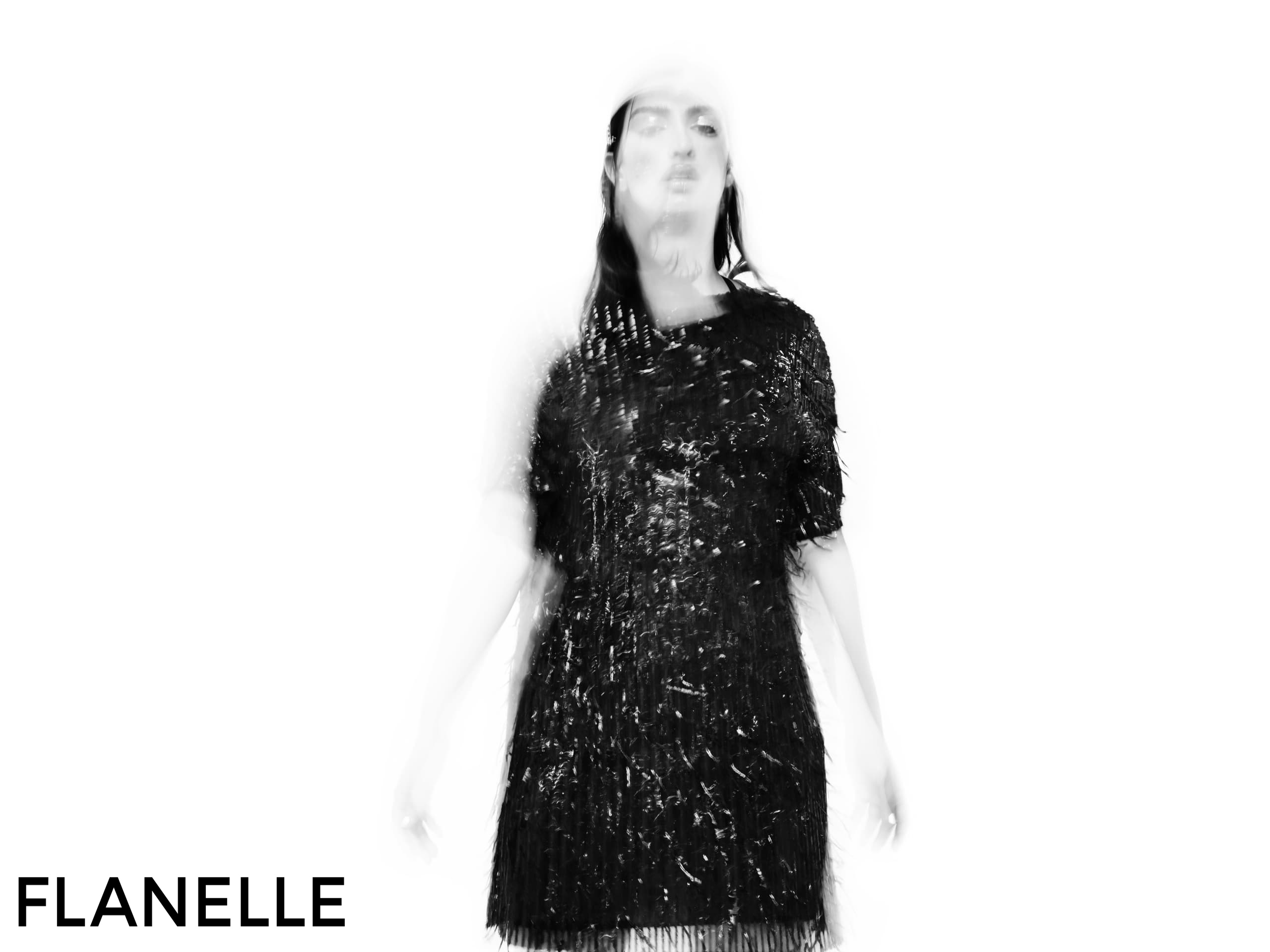 Blurred woman in black dress on white background, magazine style image.