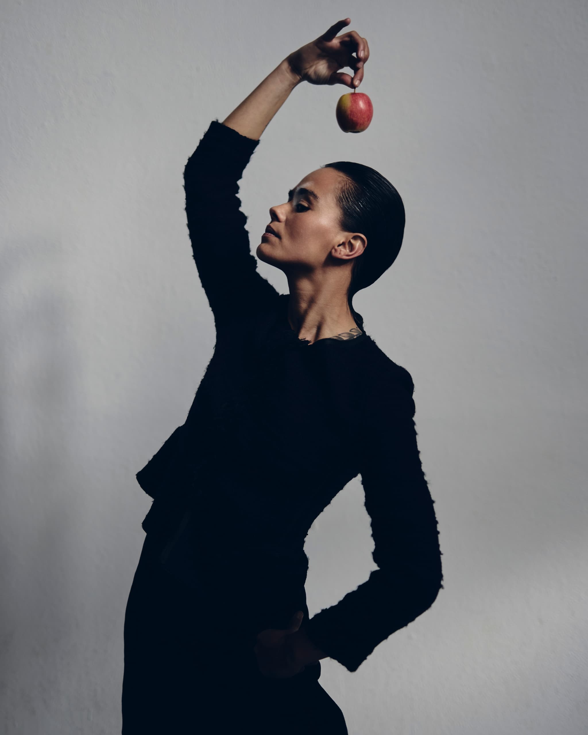 Person holding an apple elegantly against a minimalist background.