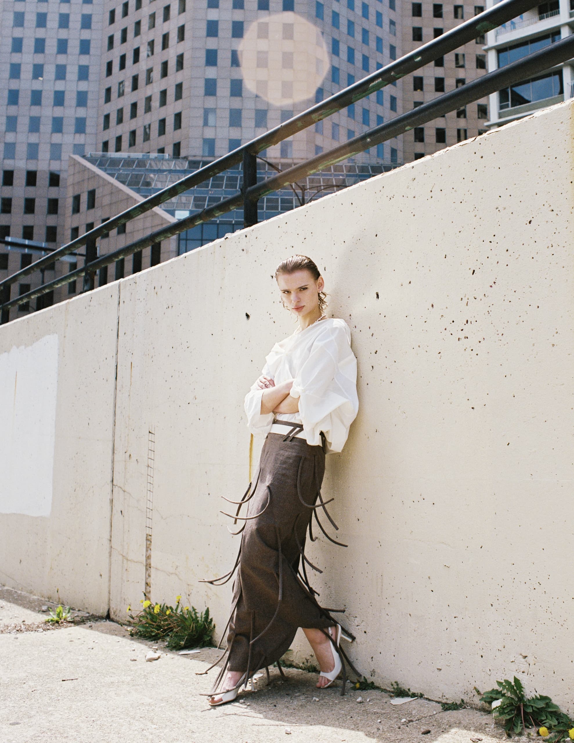 Model in stylish urban fashion poses against a city backdrop.