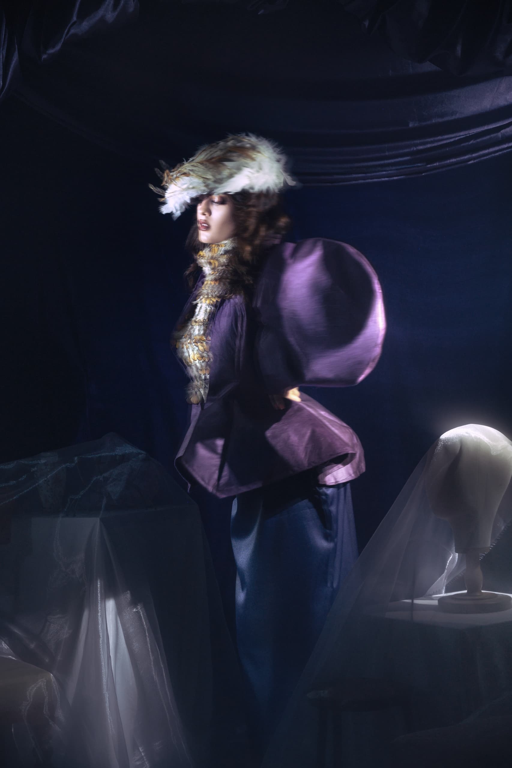 Elegant woman in vintage fashion, wearing a feathered hat in a moody setting.