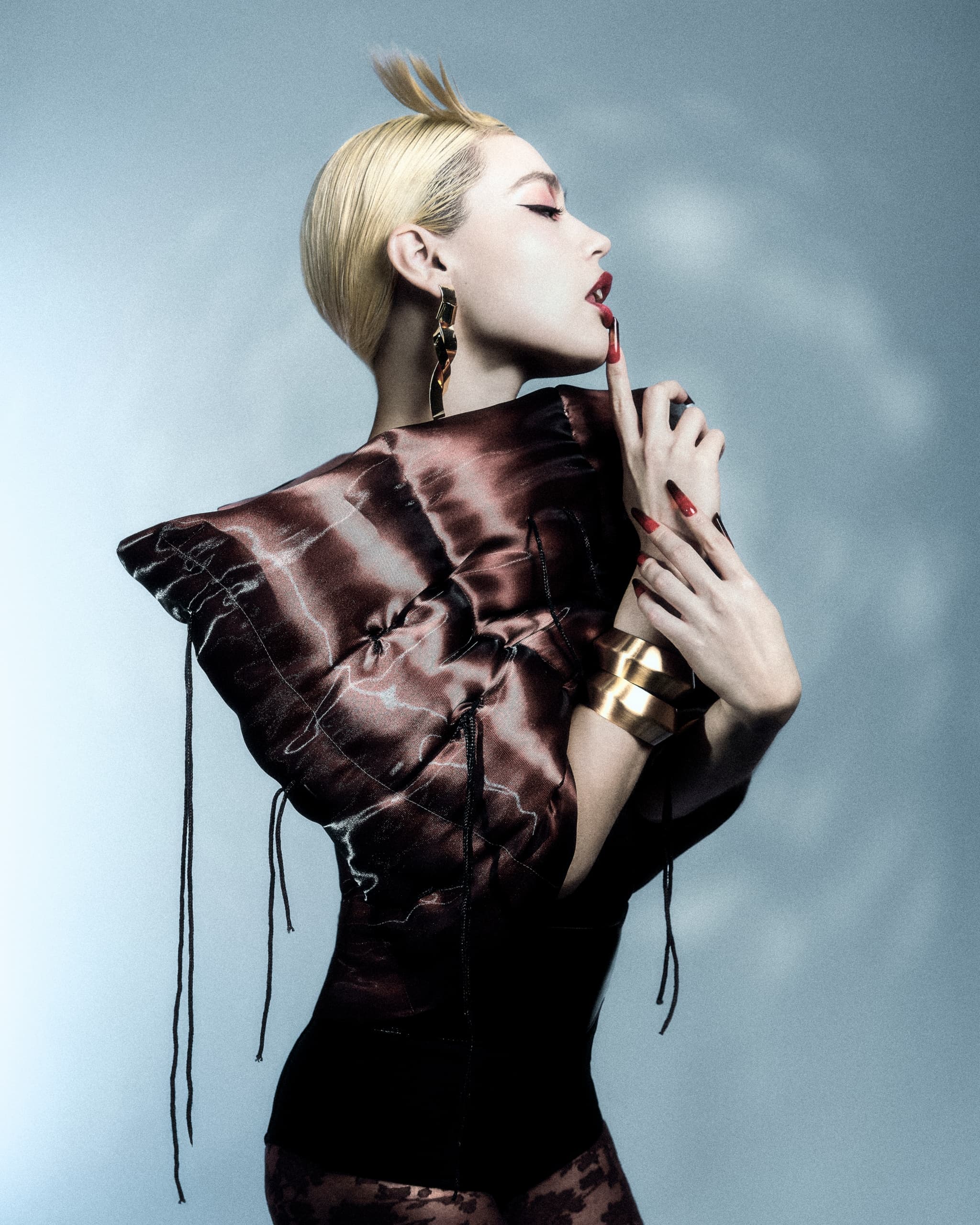 Avant-garde fashion model posing in dramatic lighting and bold outfit.