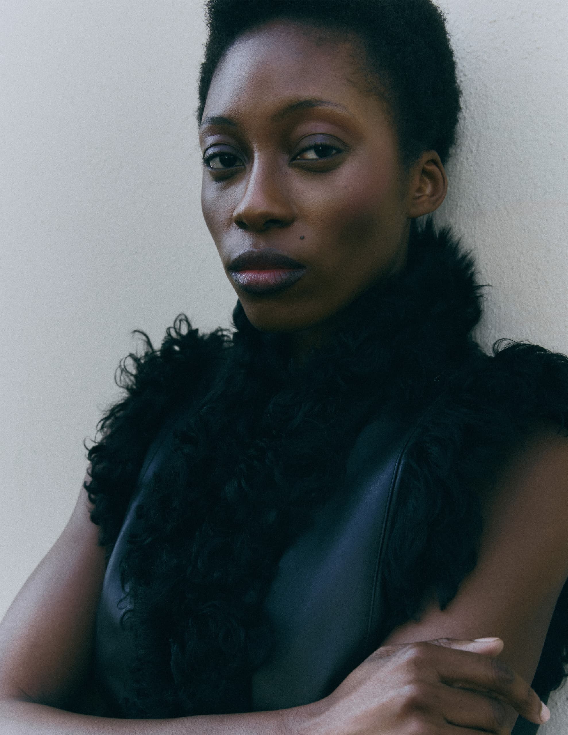 Portrait of a person in a black furry vest against a neutral background.