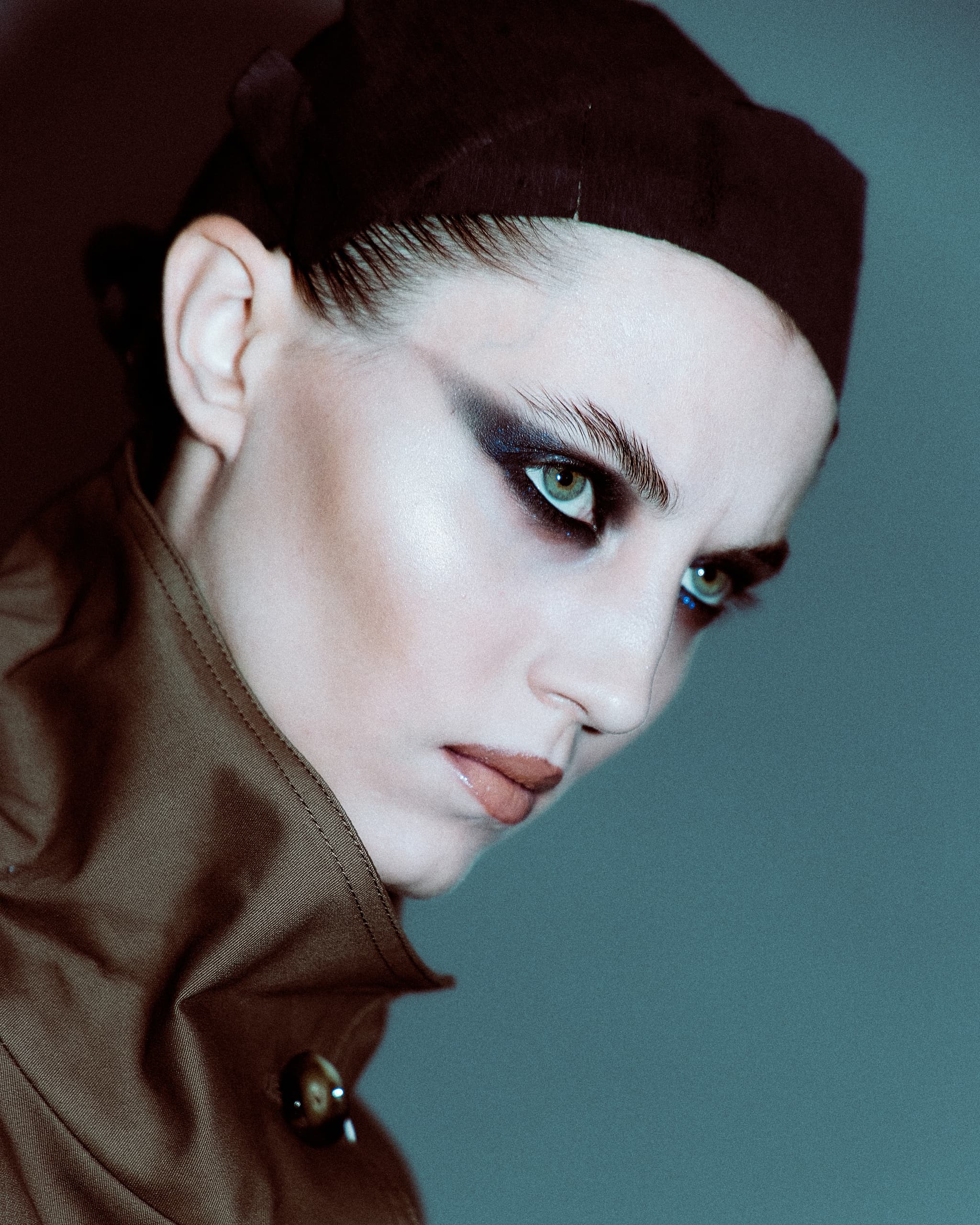 Dramatic fashion portrait with bold eye makeup and intense gaze.