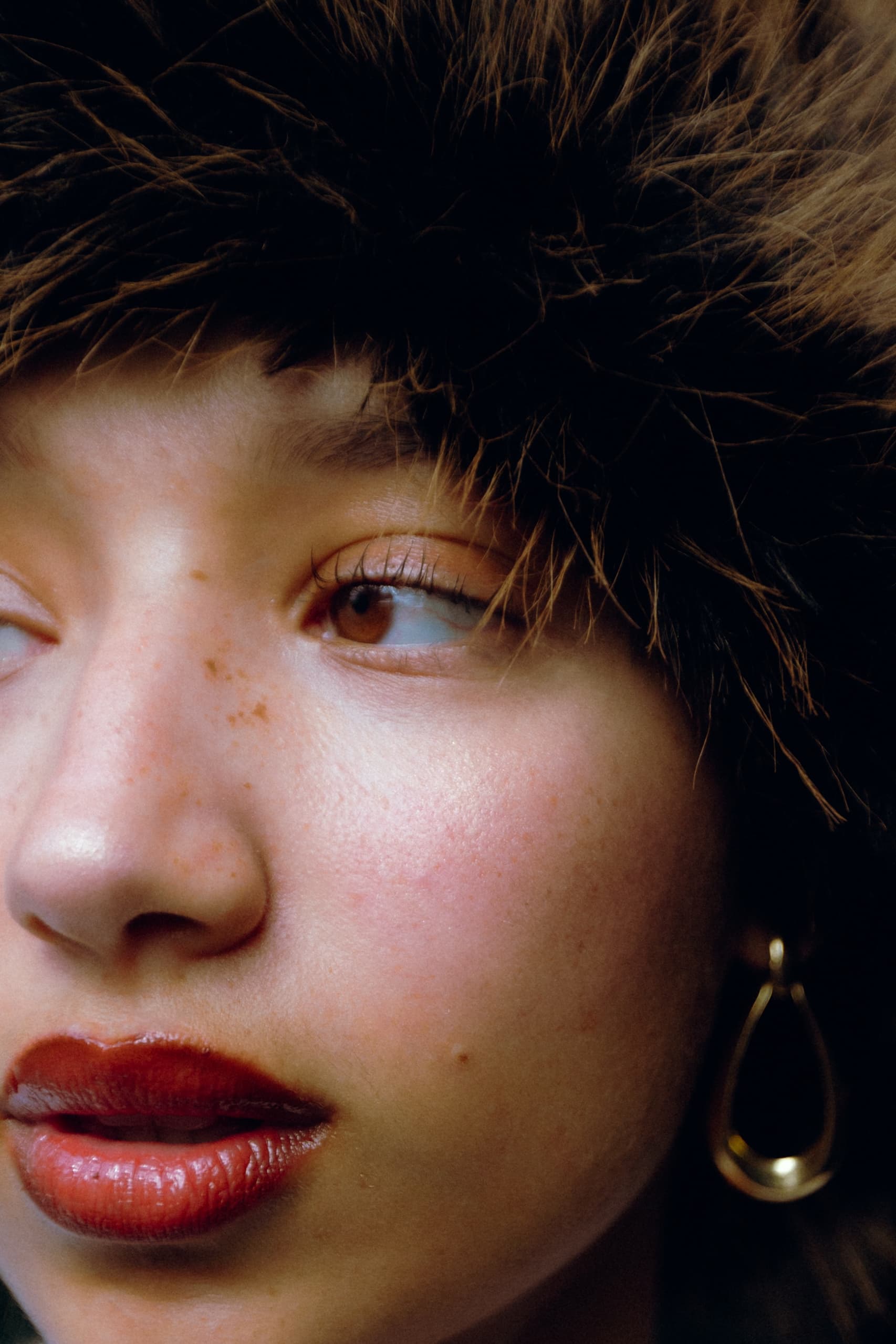 Close-up of a person wearing a fur hat and red lipstick.