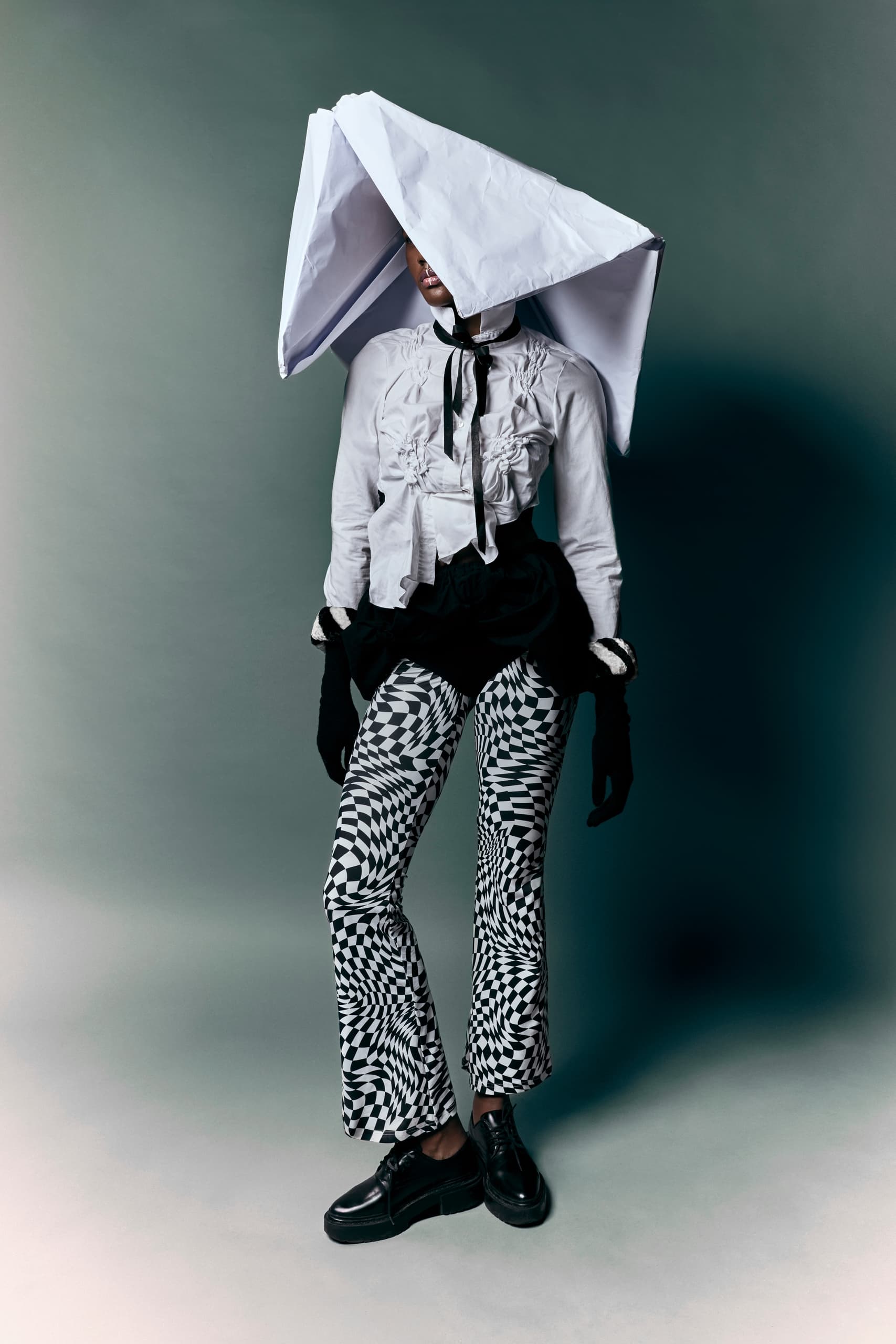 Avant-garde fashion: Optical pants, oversized paper hat, and artistic blouse.