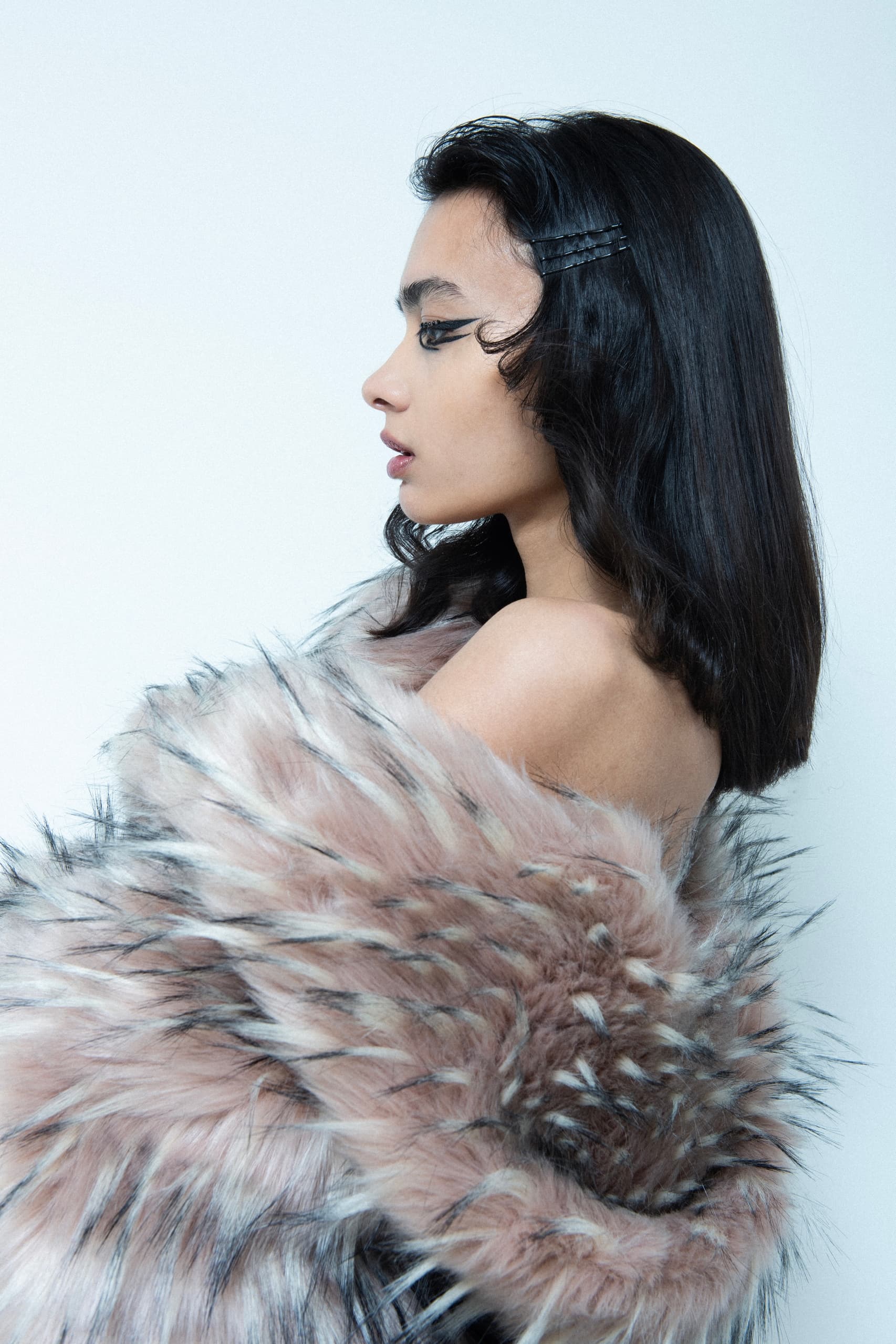 Elegant woman in fur wrap, side profile with sleek black hair.