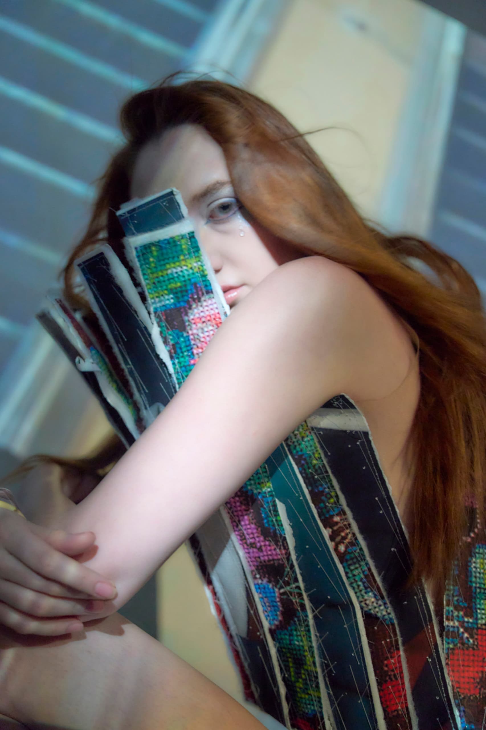 Artistic portrait with vibrant textile pattern and woman embracing artwork.