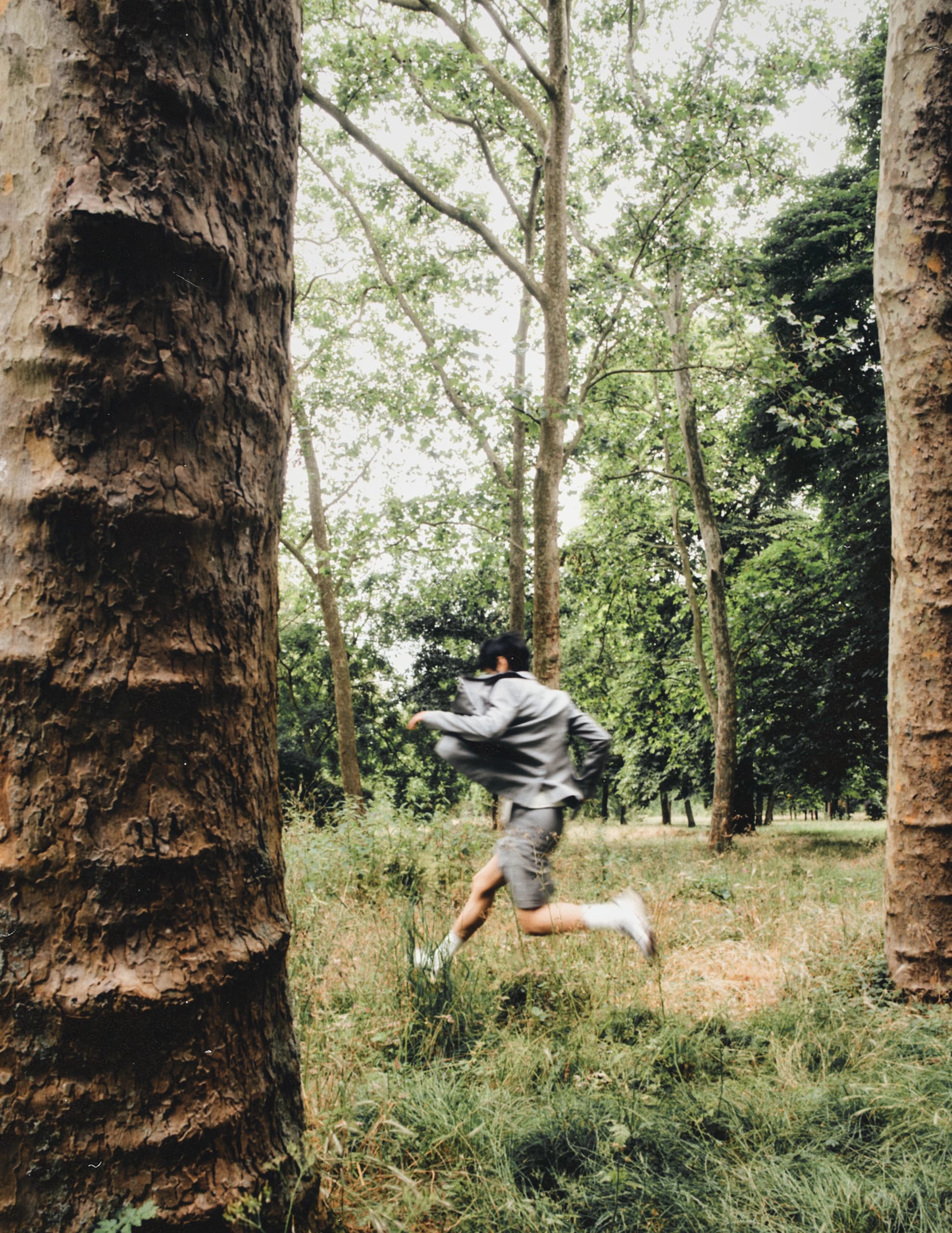 Person running through a lush green forest in casual clothes.