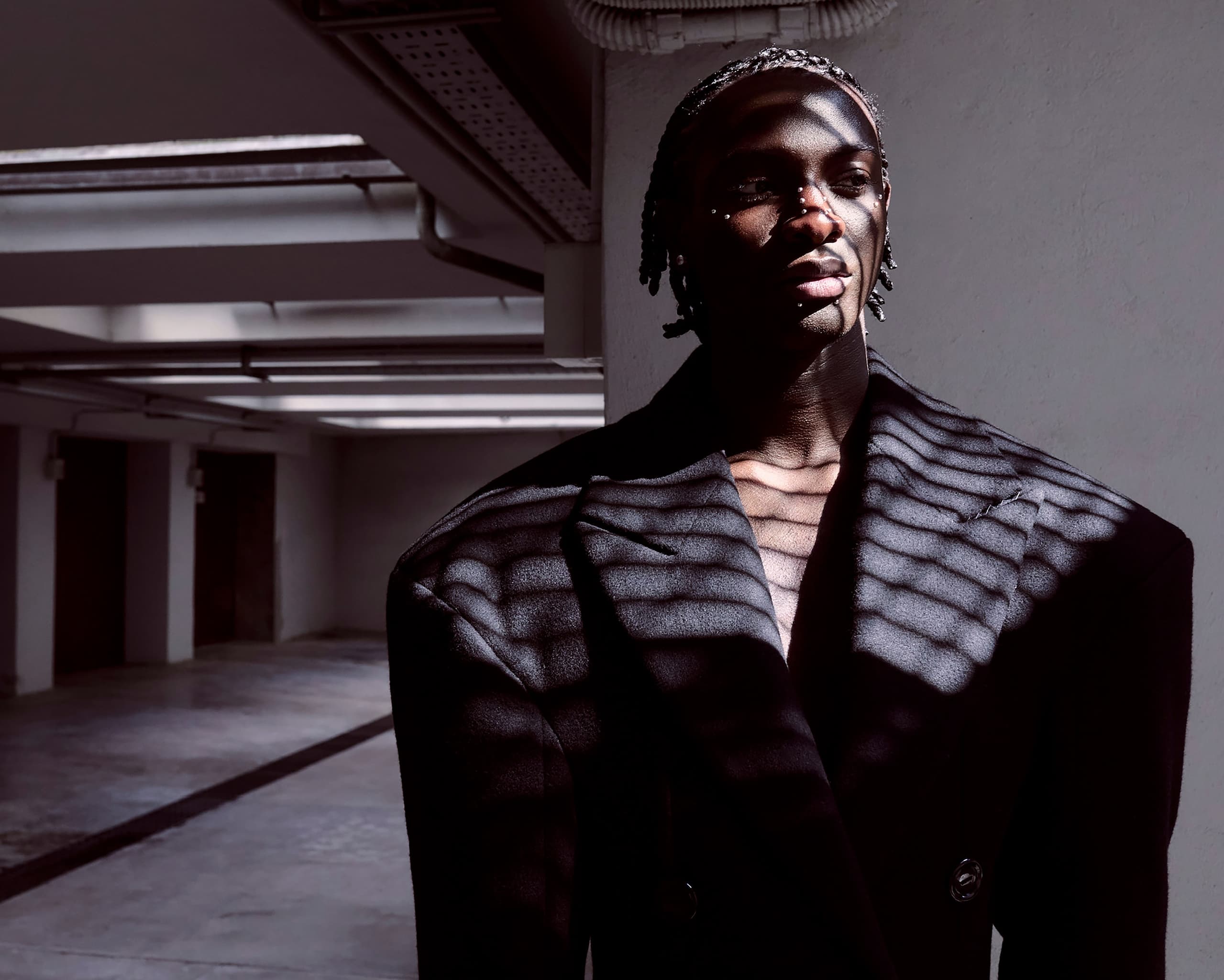 Person in shadowed light wearing a black blazer indoors.