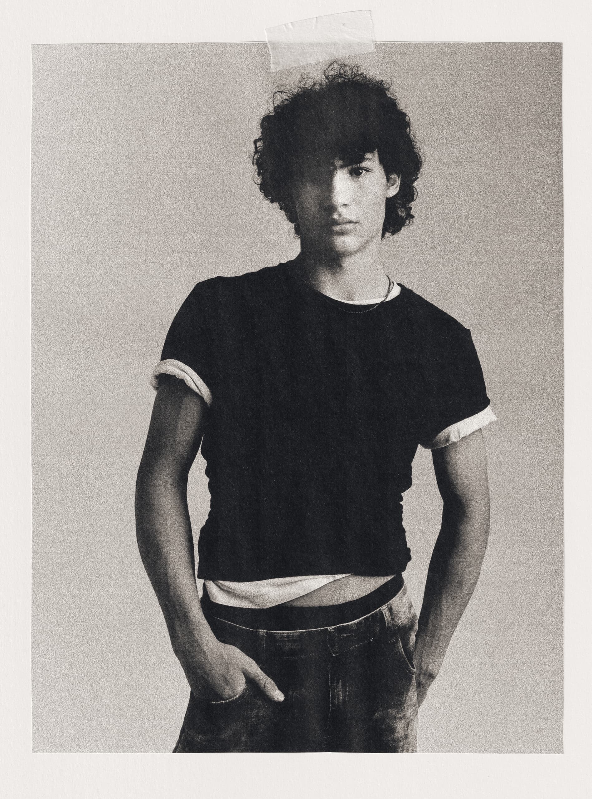 Black and white portrait of person in casual attire with hand in pocket.