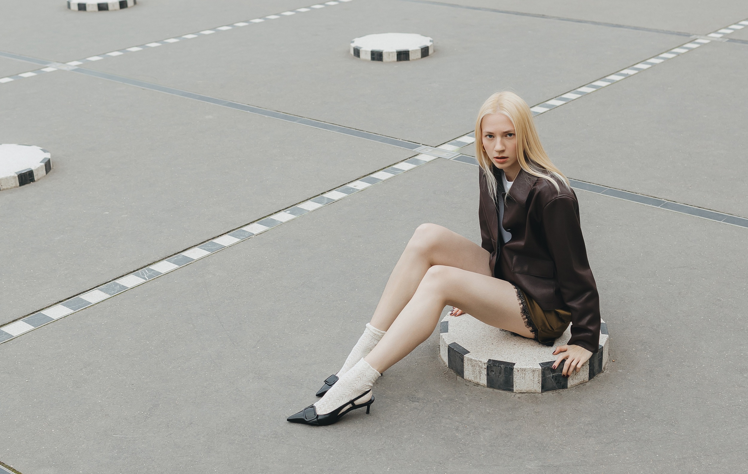 Fashionable person sitting on black and white concrete design outdoors.