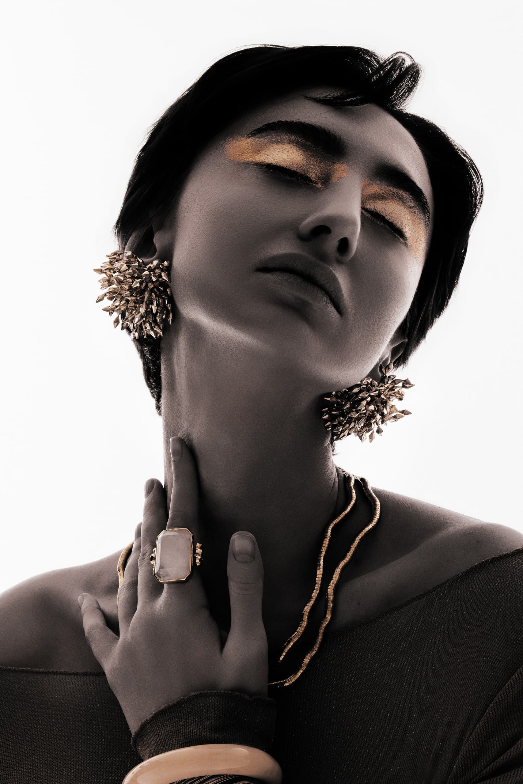 Elegant woman with gold makeup, statement earrings, and stylish jewelry.