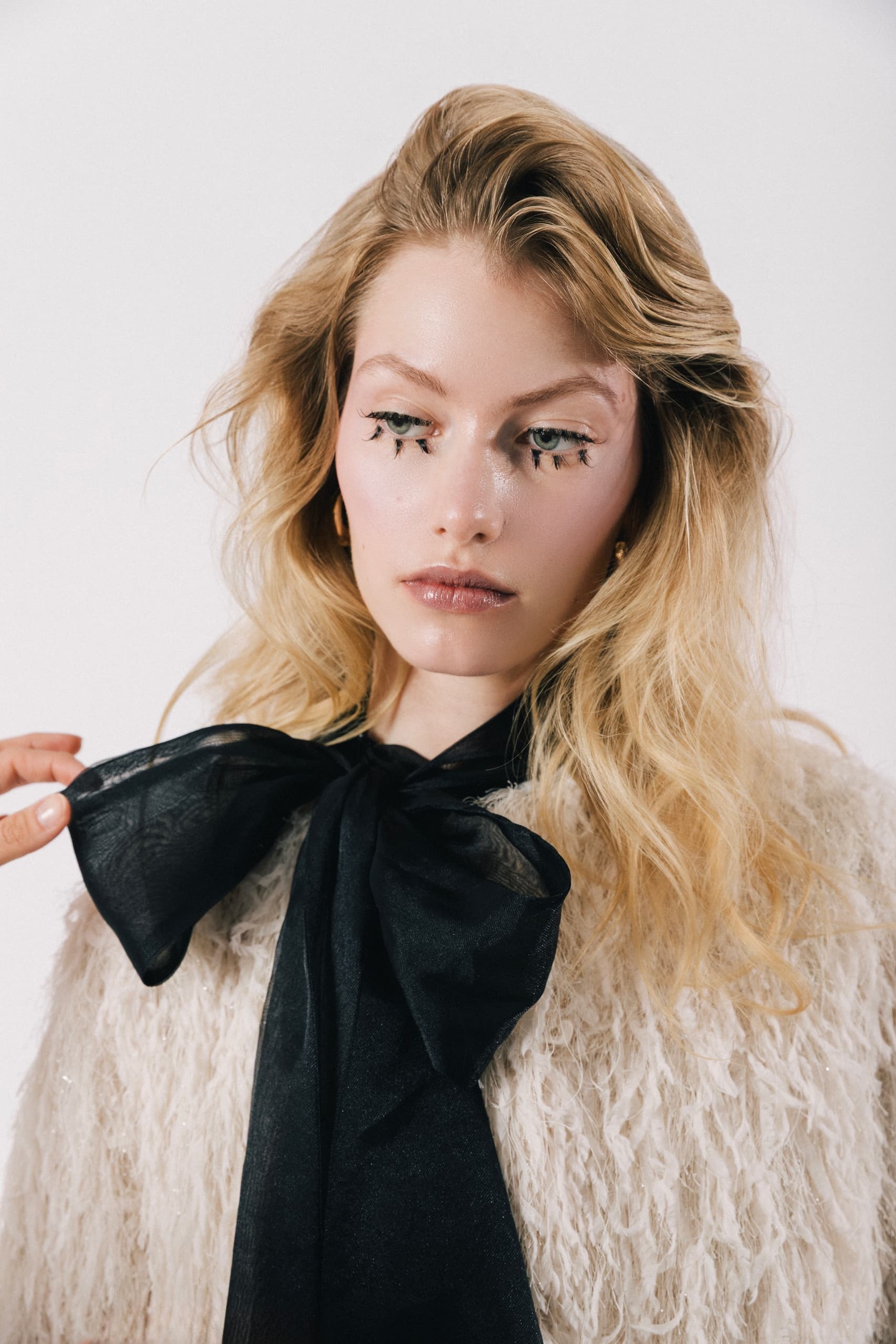 Fashionable woman in fluffy coat with bold makeup and large black bowtie.