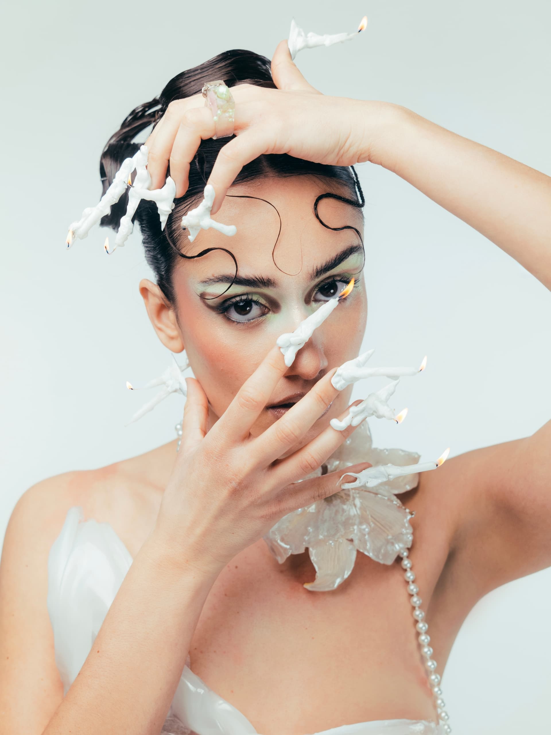 Avant-garde fashion portrait with unique candle-lit accessories and artistic makeup.