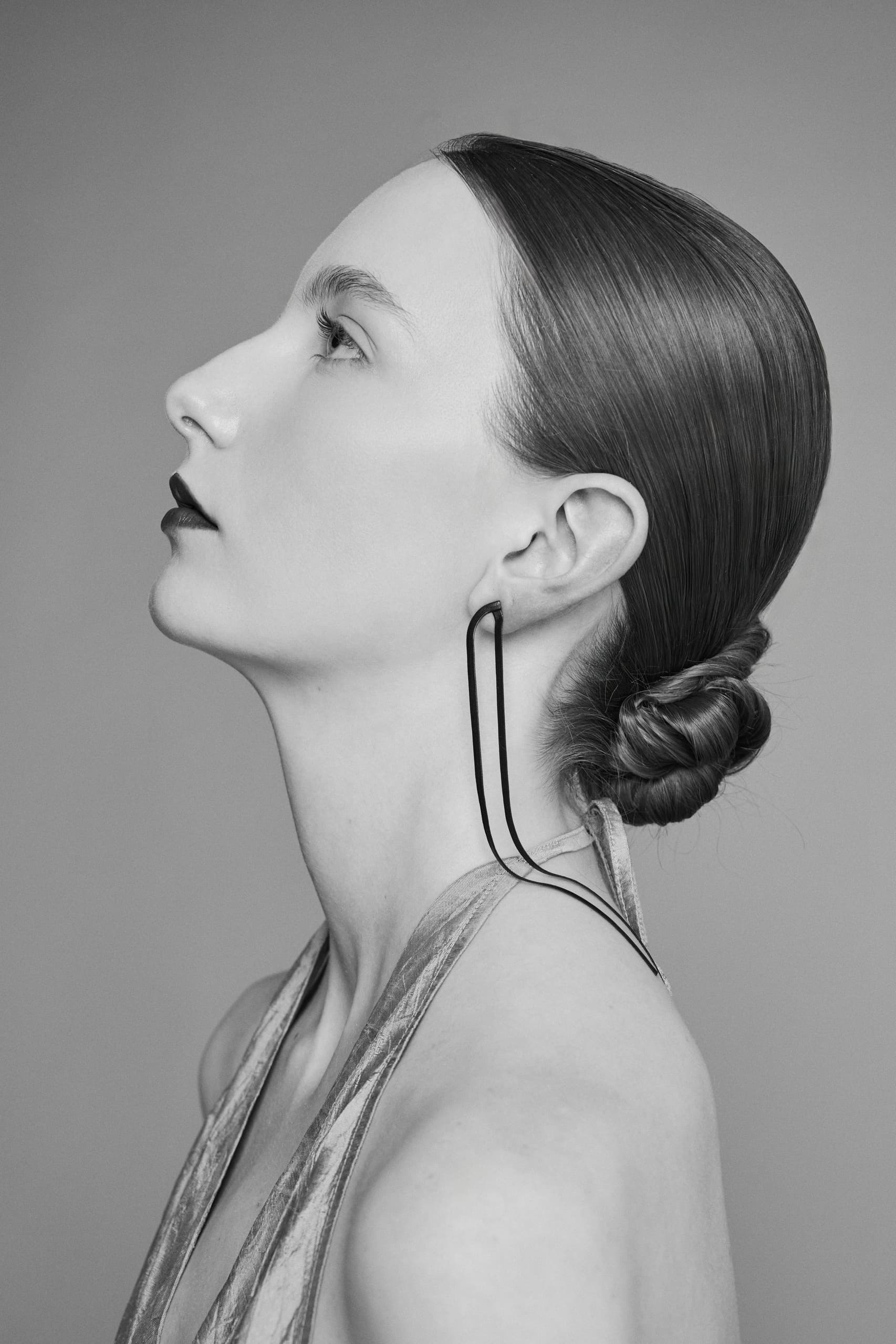 Profile of a woman with sleek hair and elegant earrings in black and white.