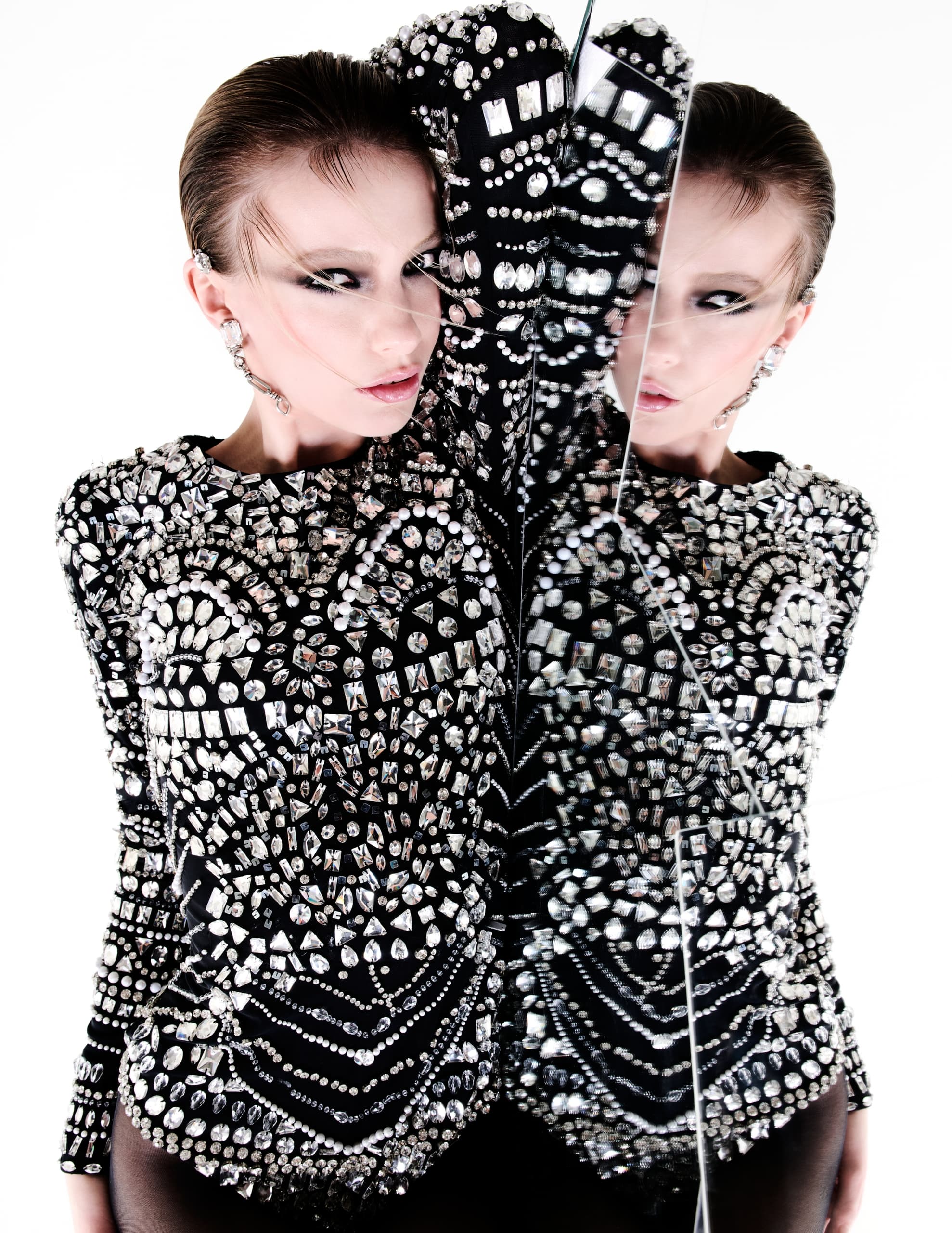 Fashion model in embellished outfit posing with a mirrored reflection.