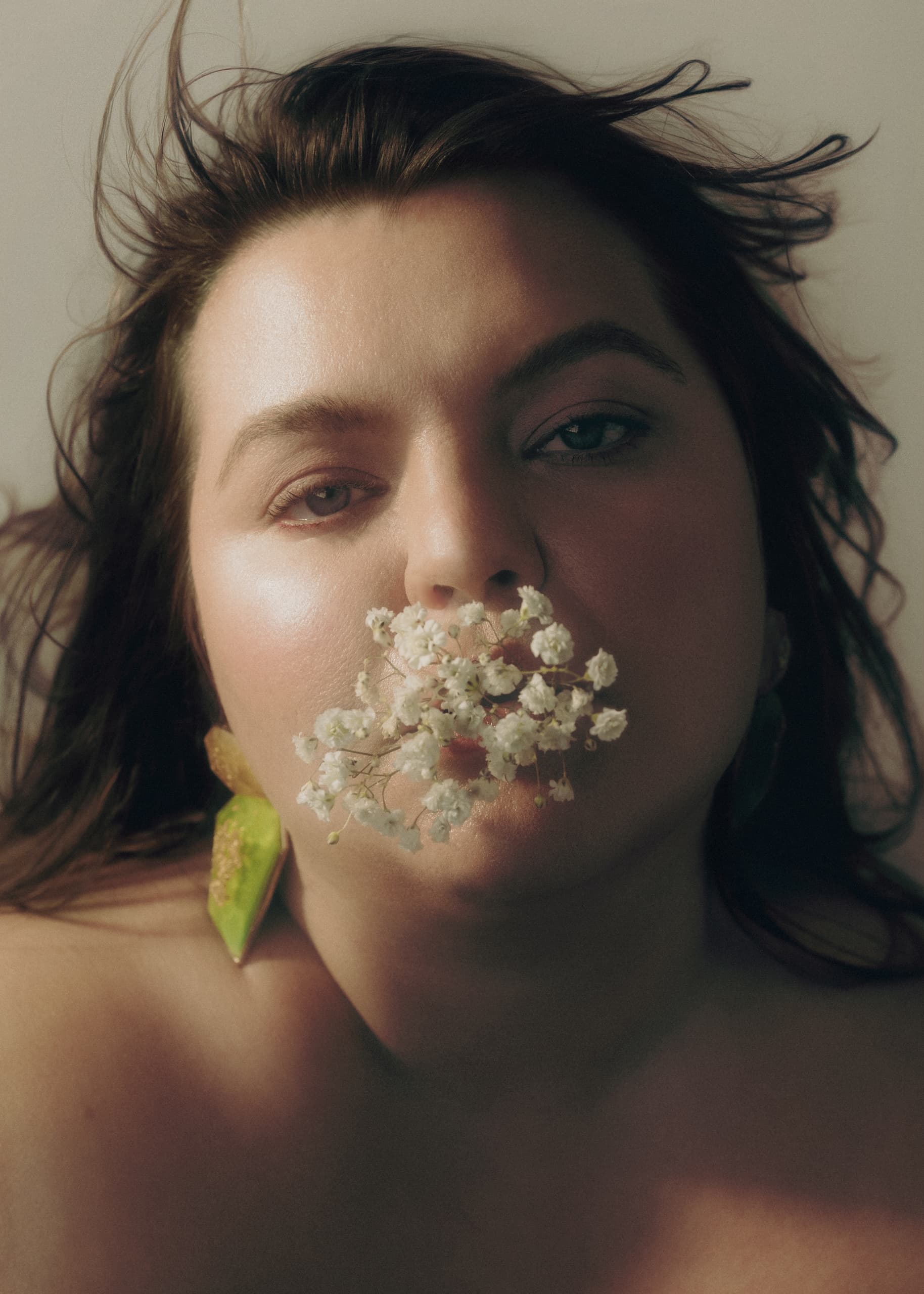 Woman with flowers in mouth, artistic portrait capturing natural beauty and expression.