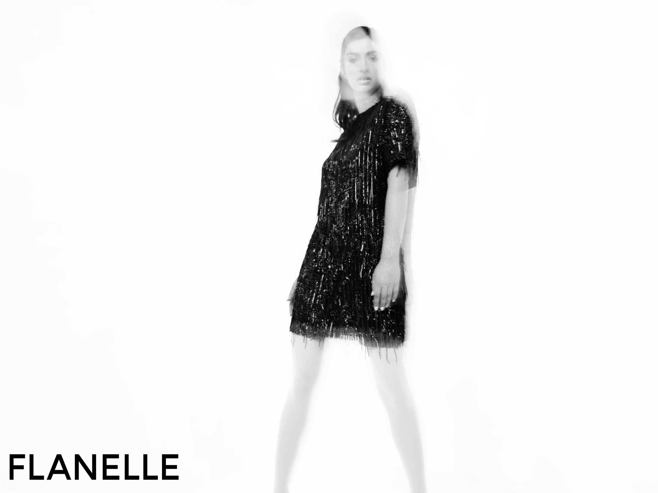 Fashion model in motion wearing a stylish black dress, artistic blur effect.