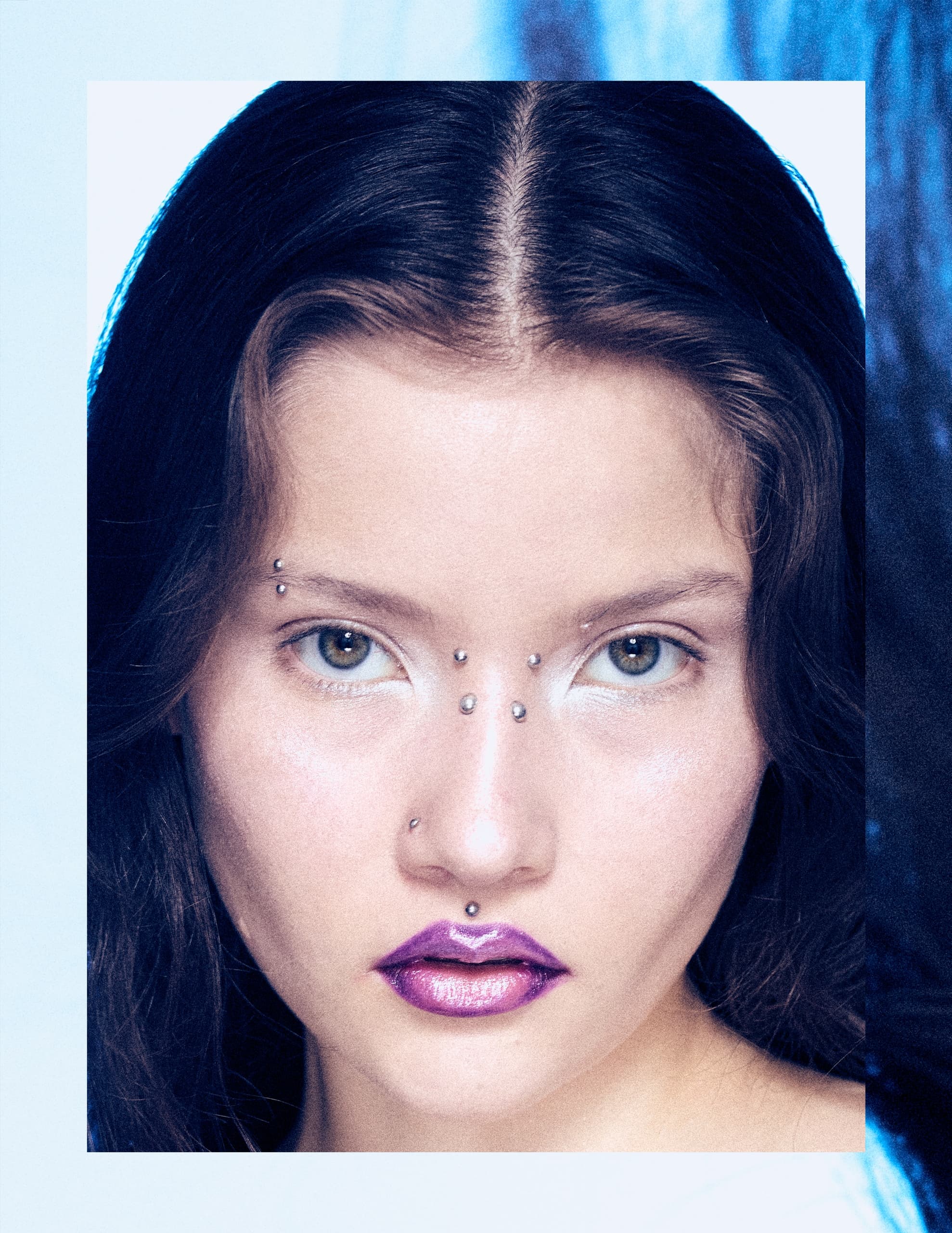 Portrait of a model with purple lipstick and facial piercings, highlighting bold style.