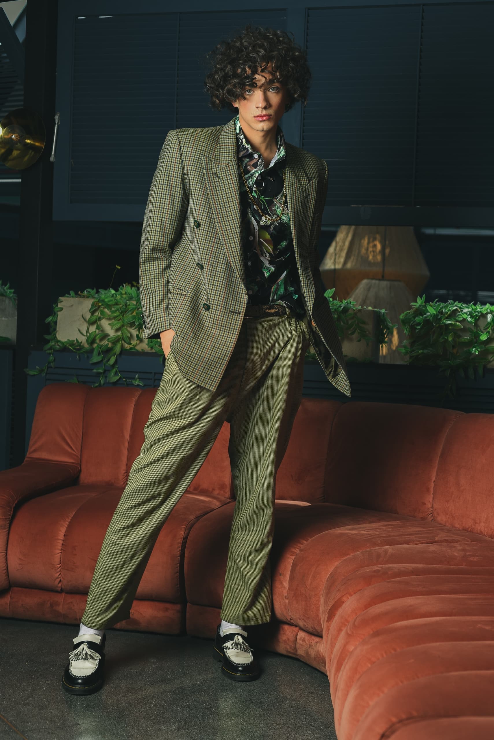 Stylish person in a plaid suit posing in a chic indoor setting.