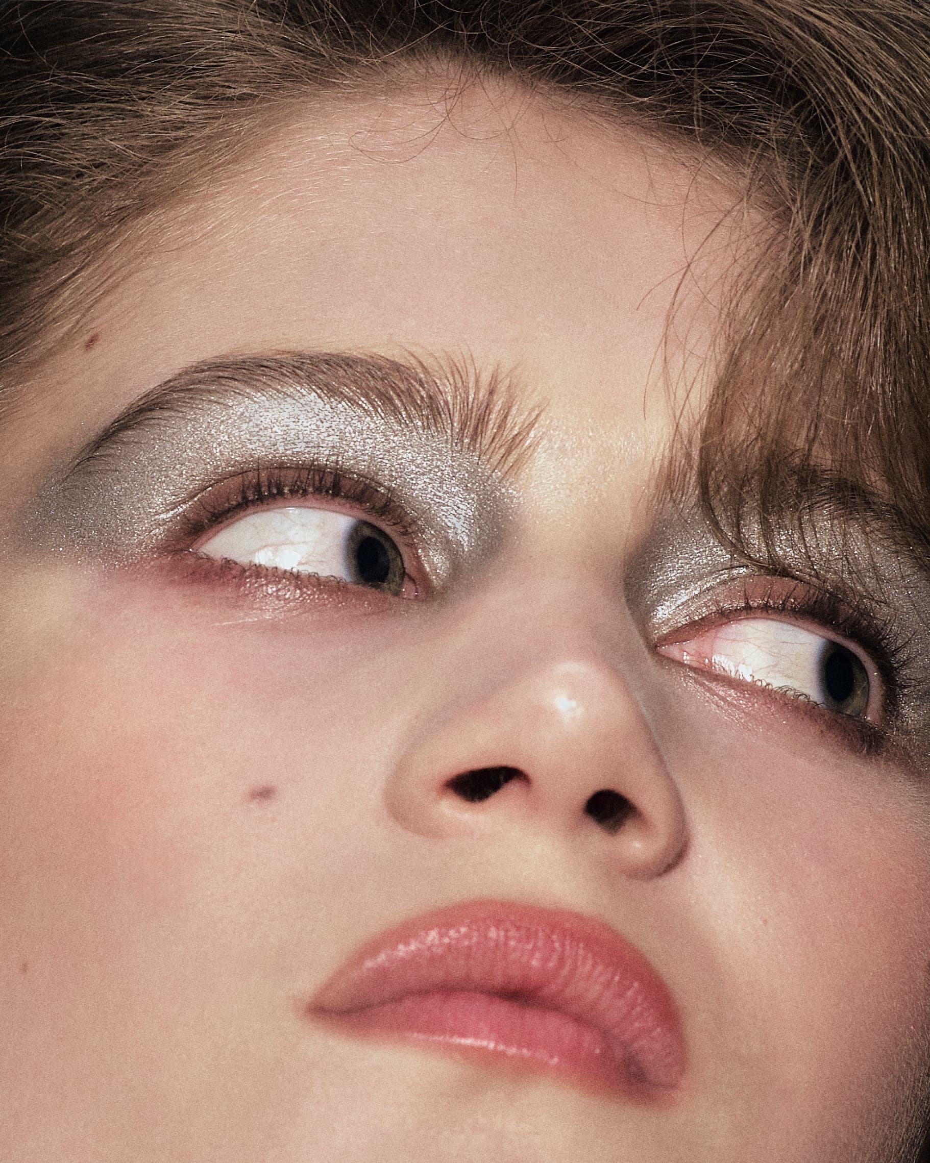 Close-up of a person with shimmering silver eye makeup and natural lip color.