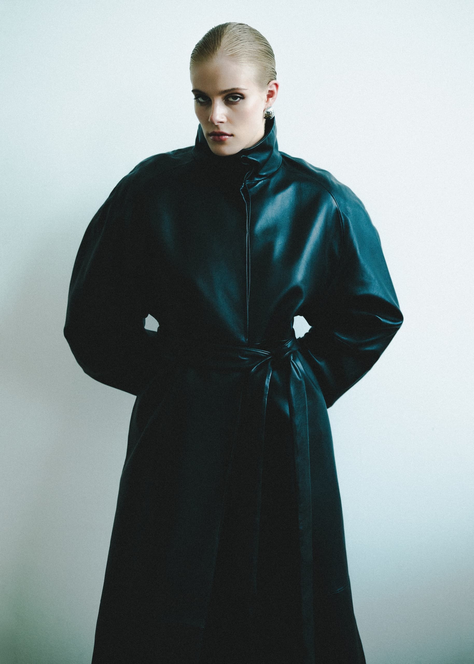 Person in black leather coat, stylish fashion portrait against white background.