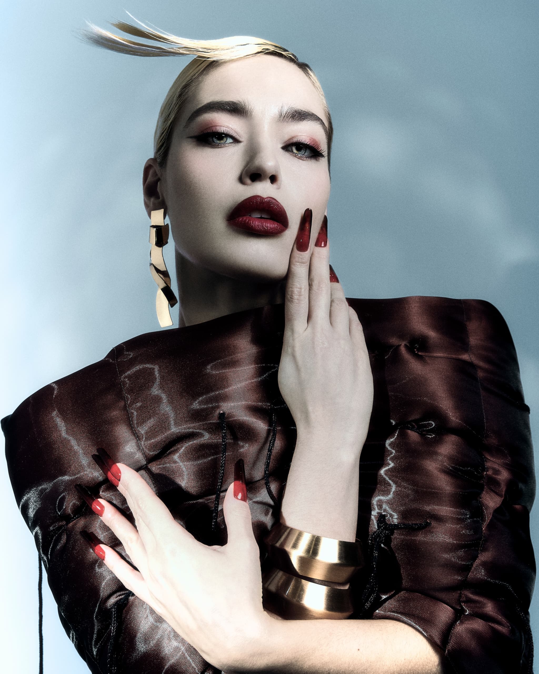 Stylish model in avant-garde fashion with bold red lips and sleek hairstyle.