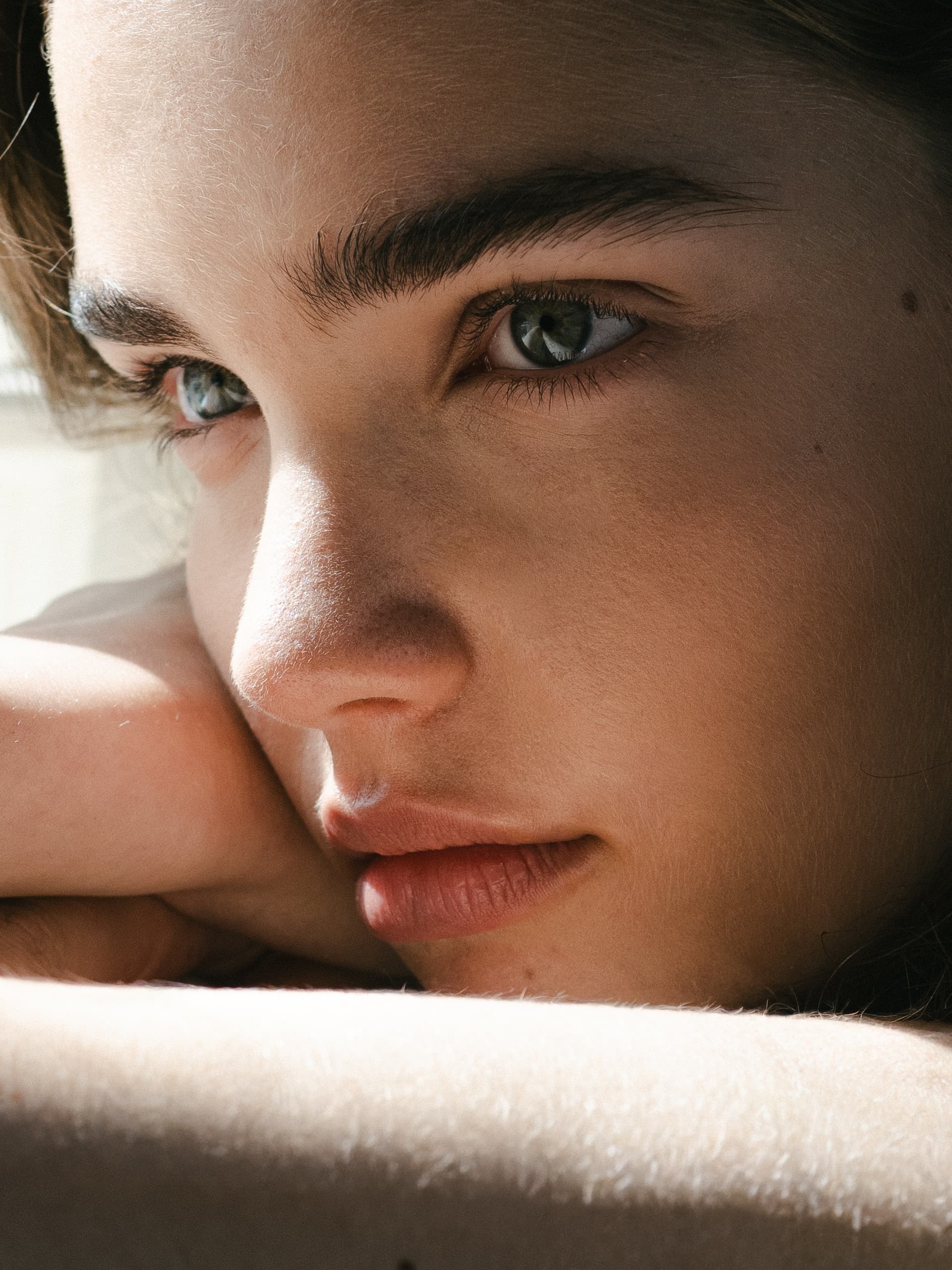 Close-up of a person's pensive eyes and face, with soft natural lighting.