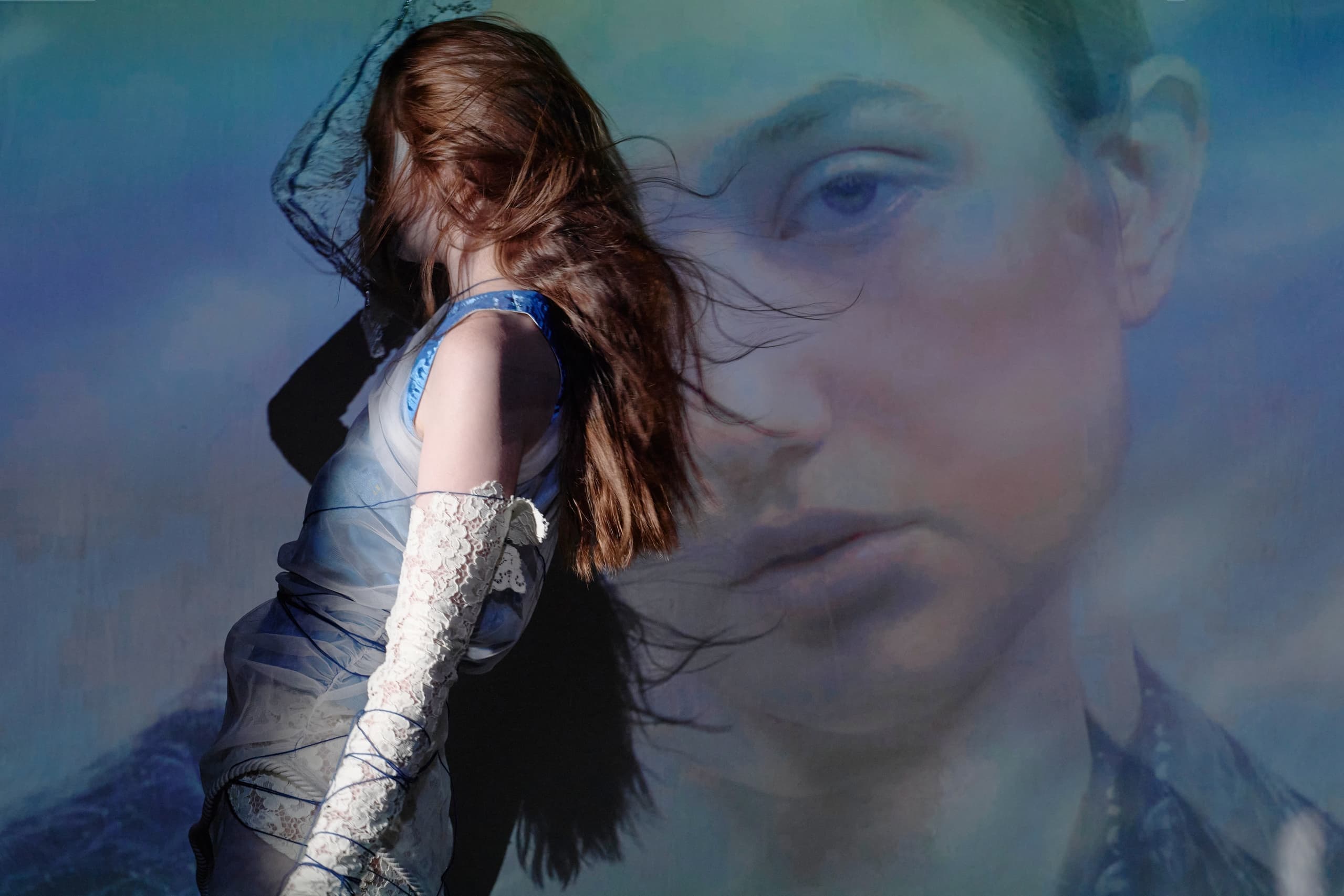 Artistic woman in a blue dress with dreamy background projection.
