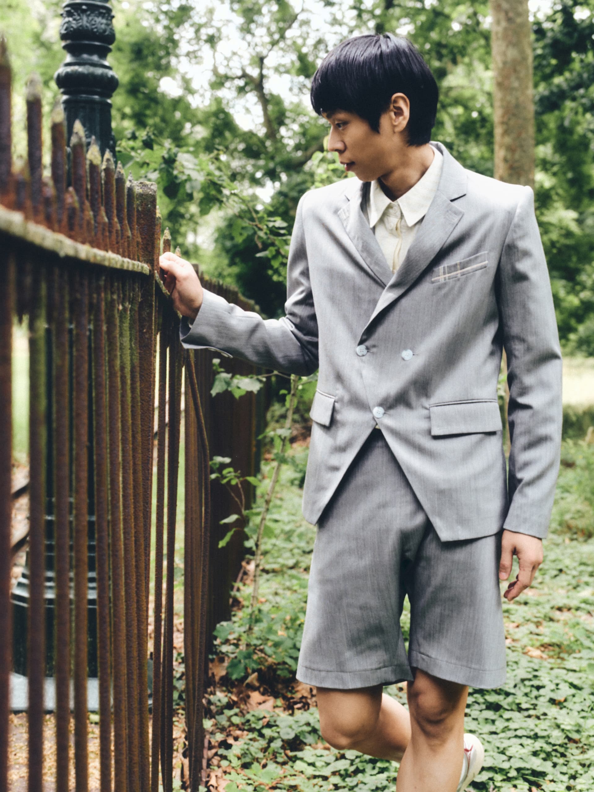 Man in a gray suit exploring a lush, green outdoor setting.