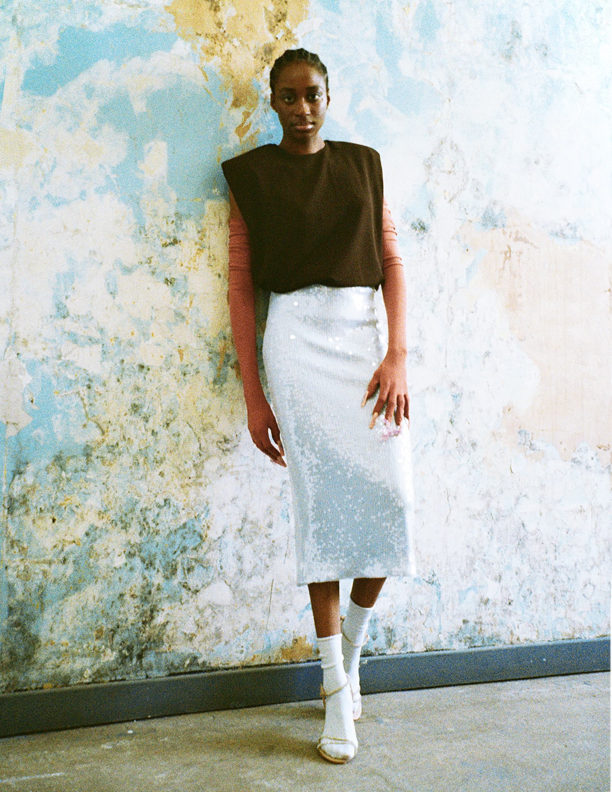 Fashionable woman in a chic outfit against textured wall.