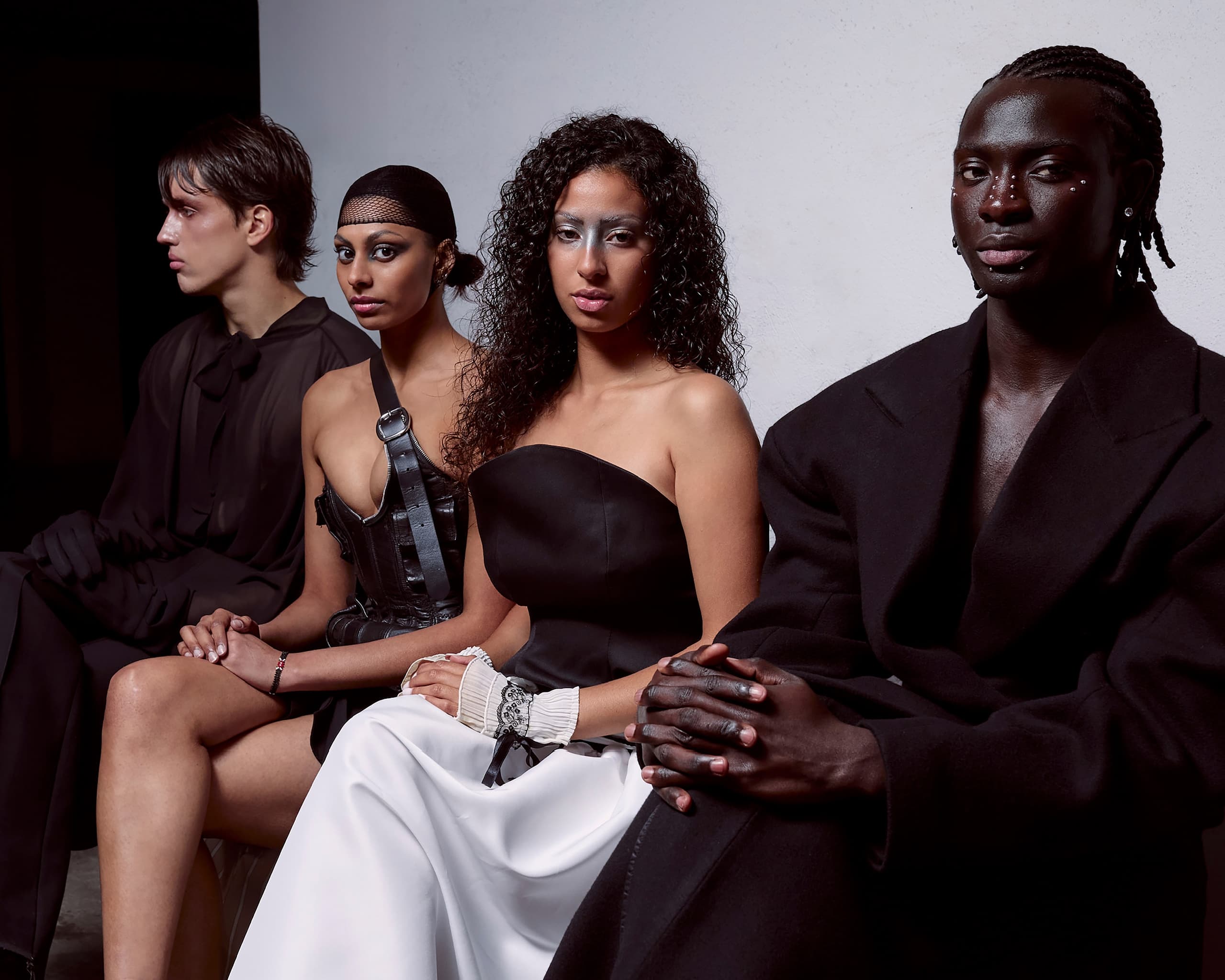 Fashion models sitting in elegant, modern attire, showcasing diverse styles.