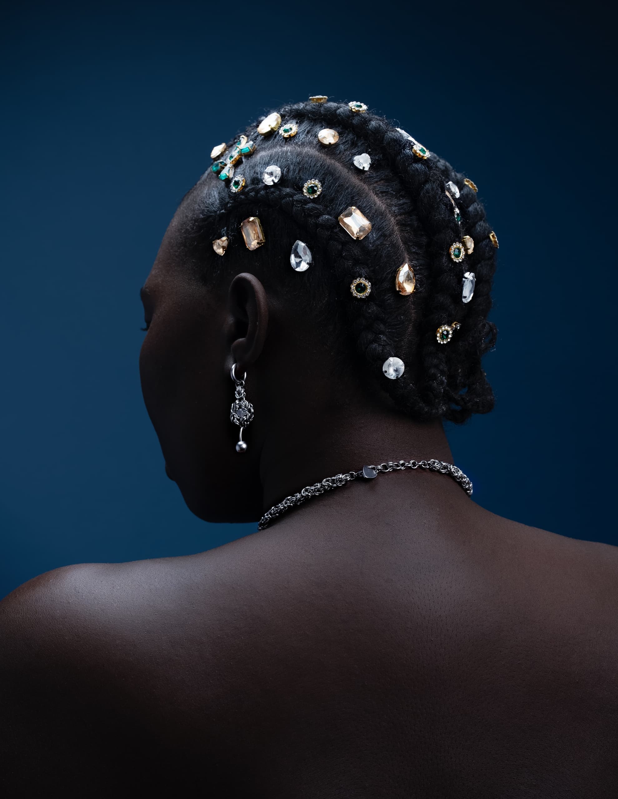 Elegant braids adorned with jewels and gemstones against a dark blue background.