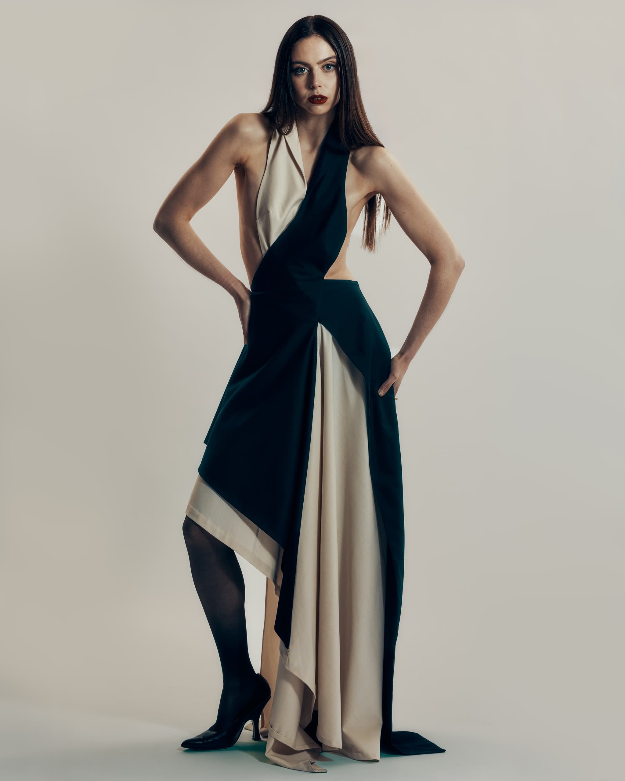Woman in elegant black and white dress striking a fashion pose.