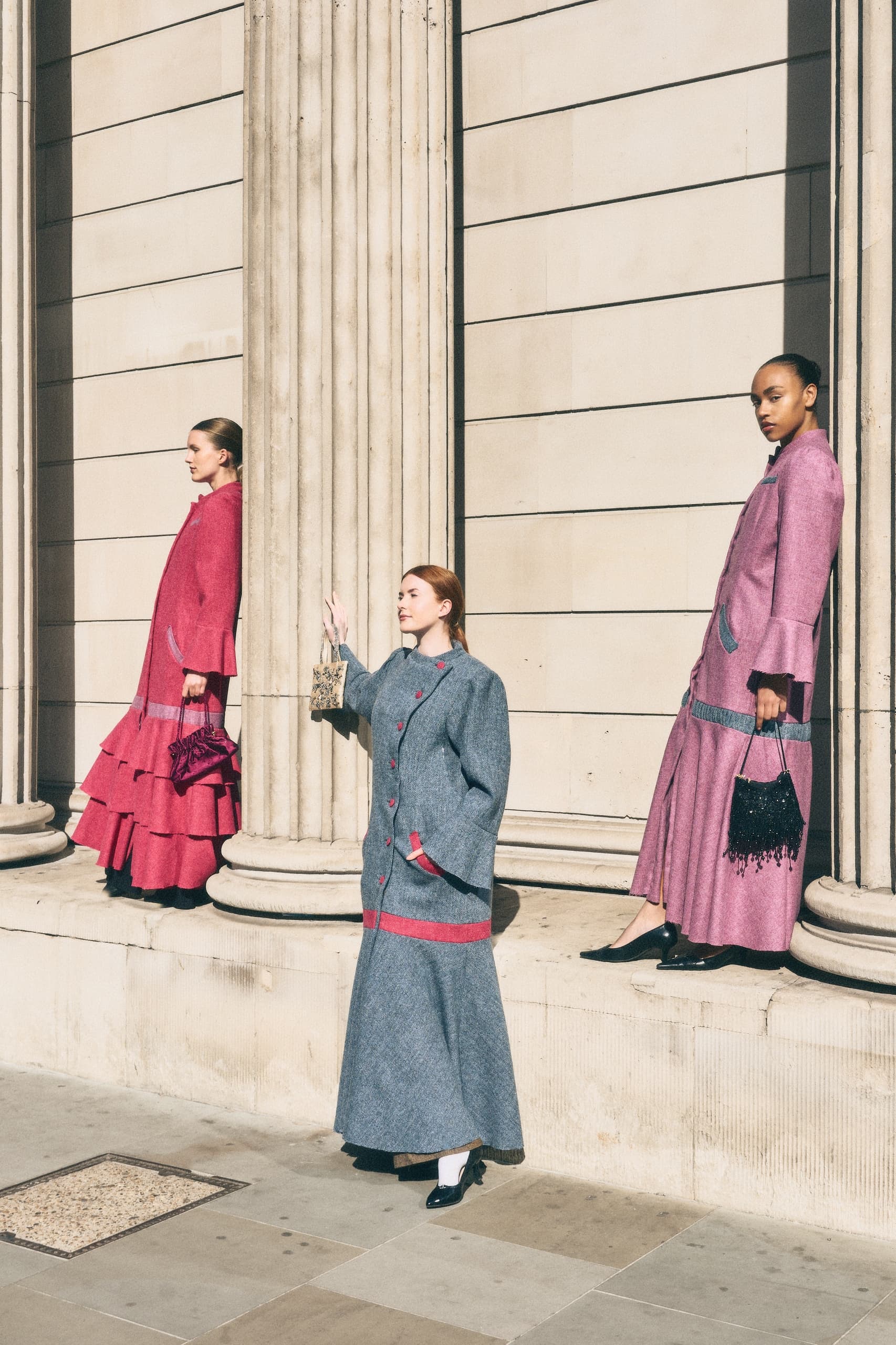 Models in vibrant fashion outfits pose against classic architecture.