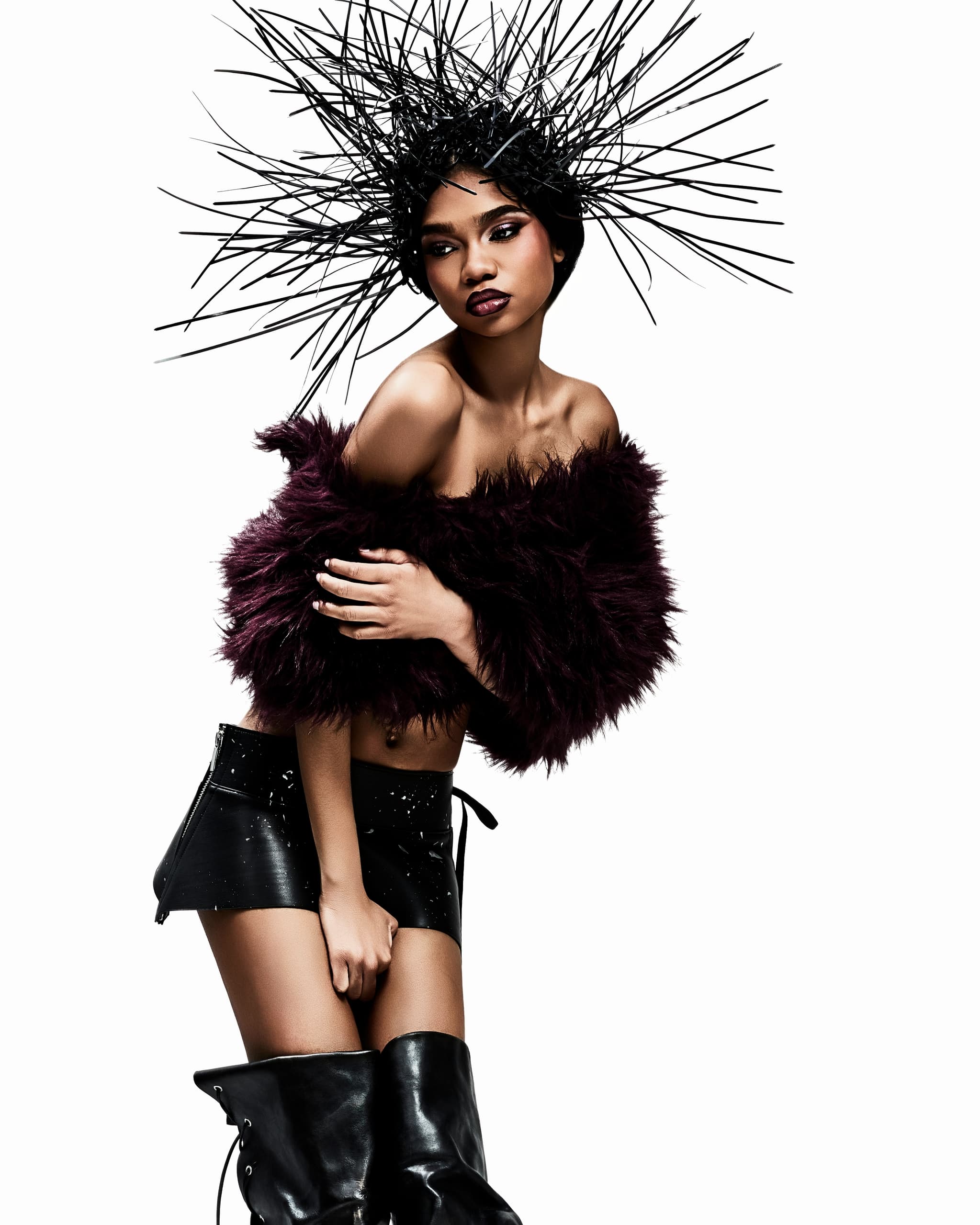 Fashion model in avant-garde outfit with spiky headpiece and fur top.