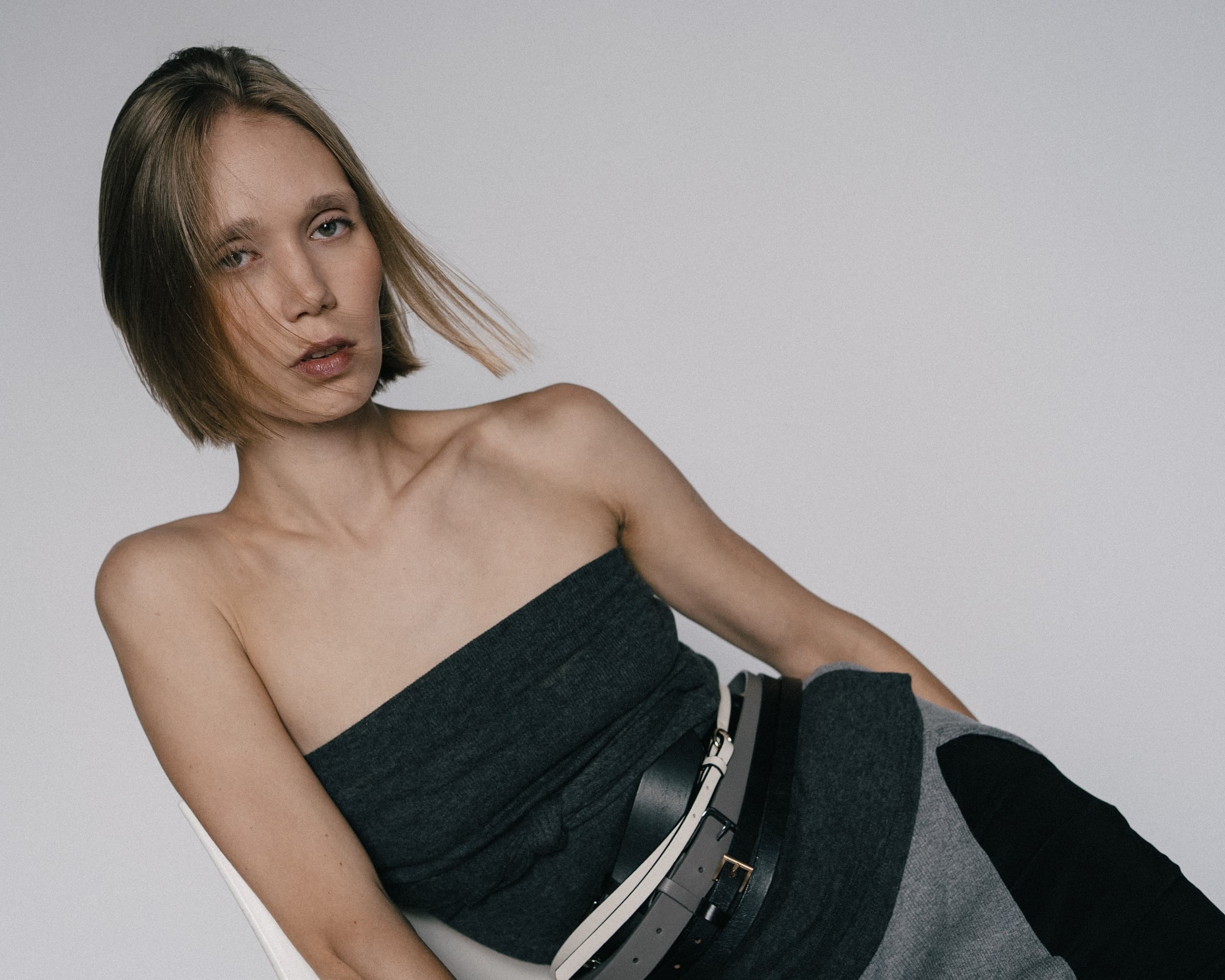 Fashionable woman in a strapless outfit with sleek hair and modern accessories.