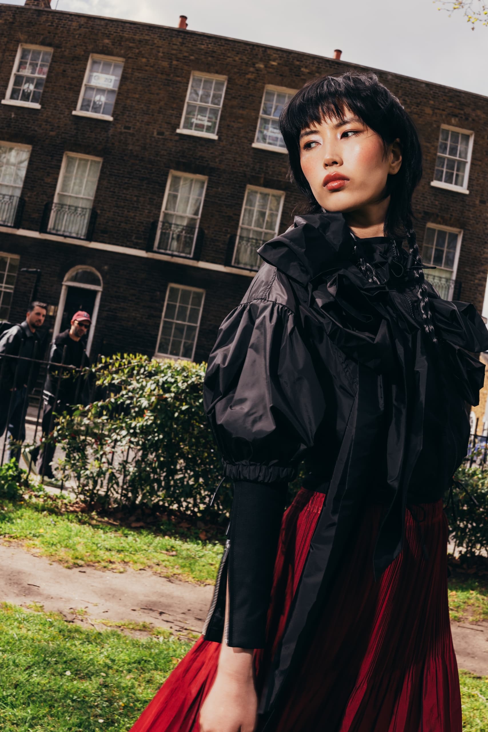 Fashionable woman in black and red, urban background with brick building.