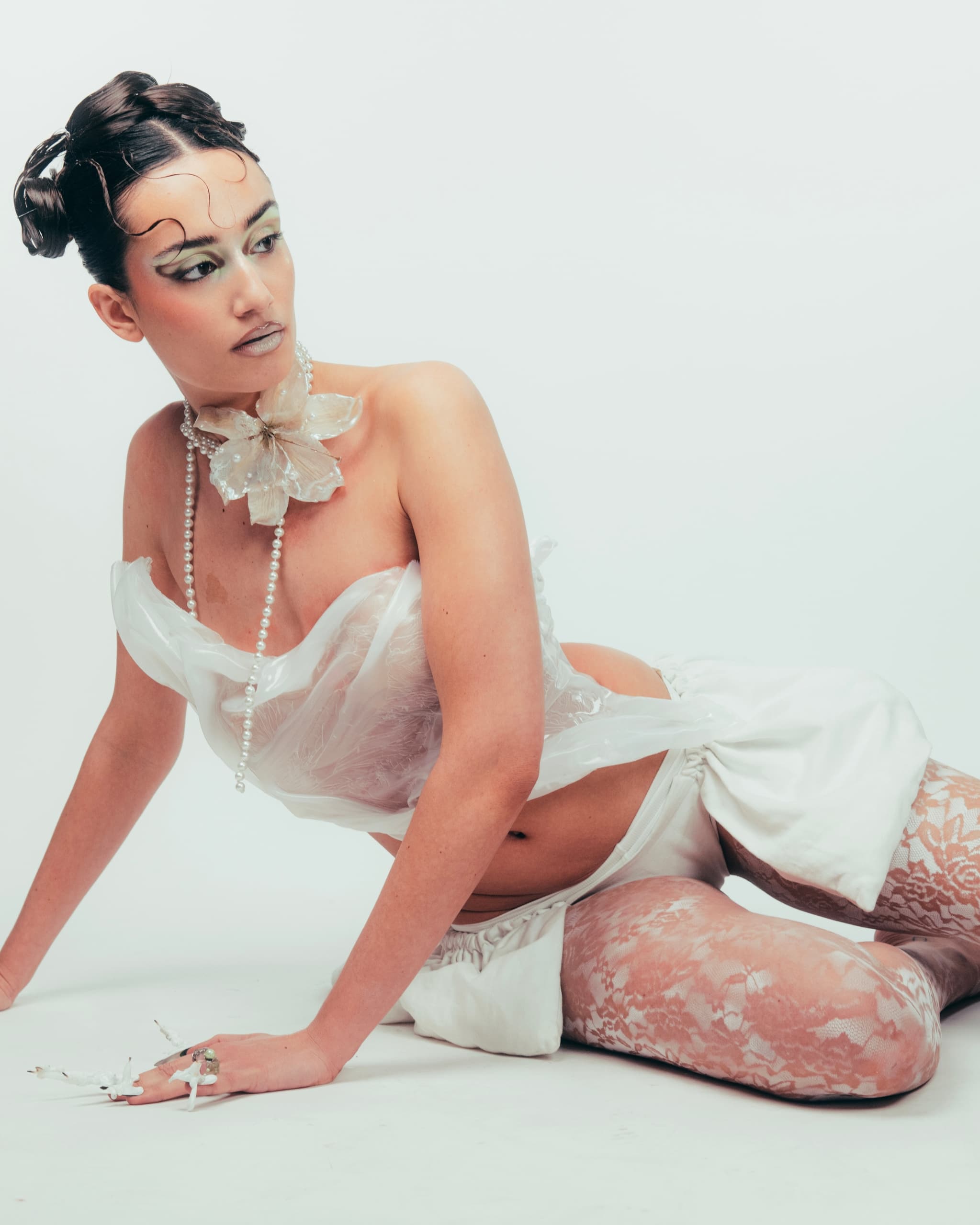 Woman in avant-garde fashion with lace tights and floral accessories, posing elegantly.