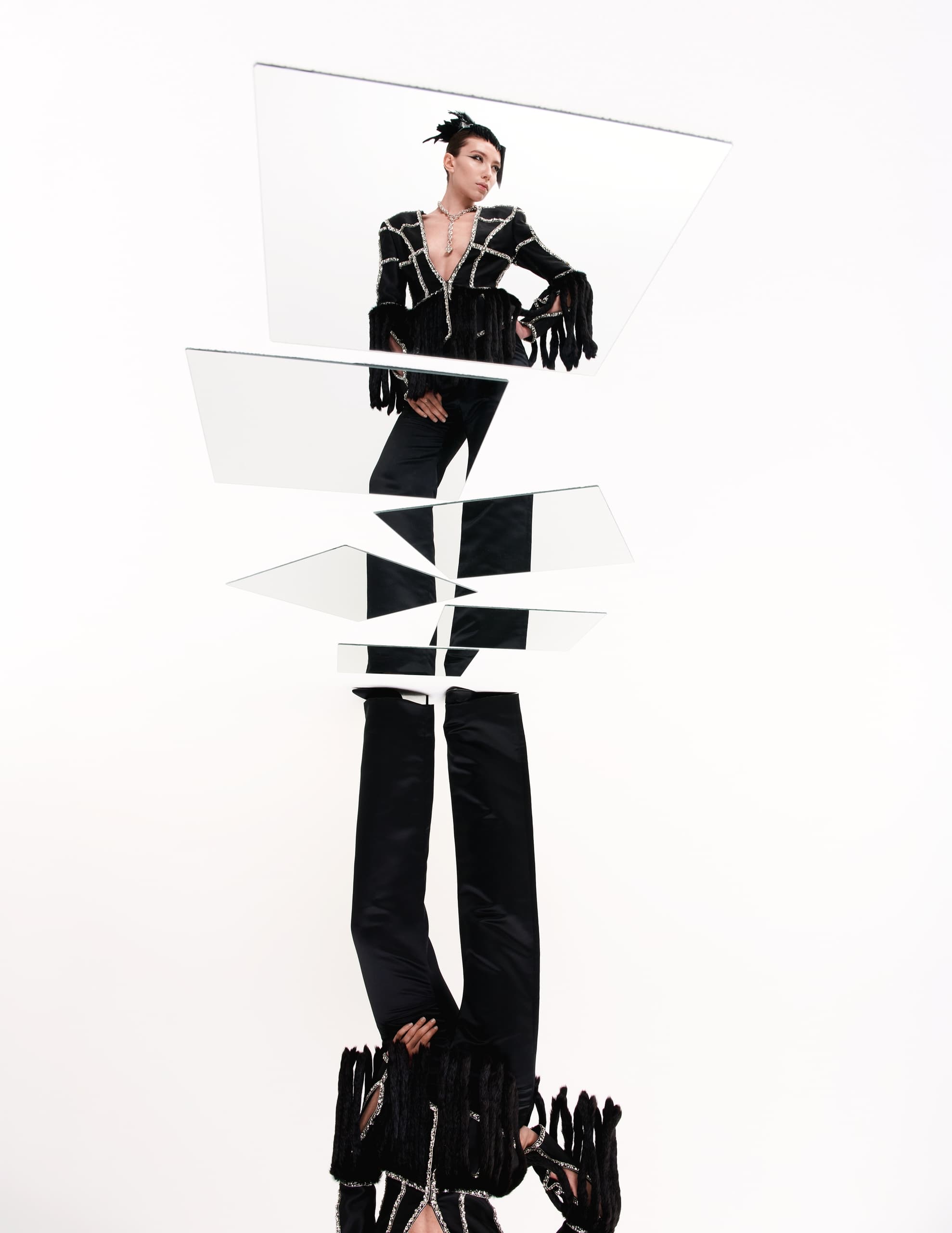 Fashion model posing with fragmented mirror reflections, in black fringe outfit.