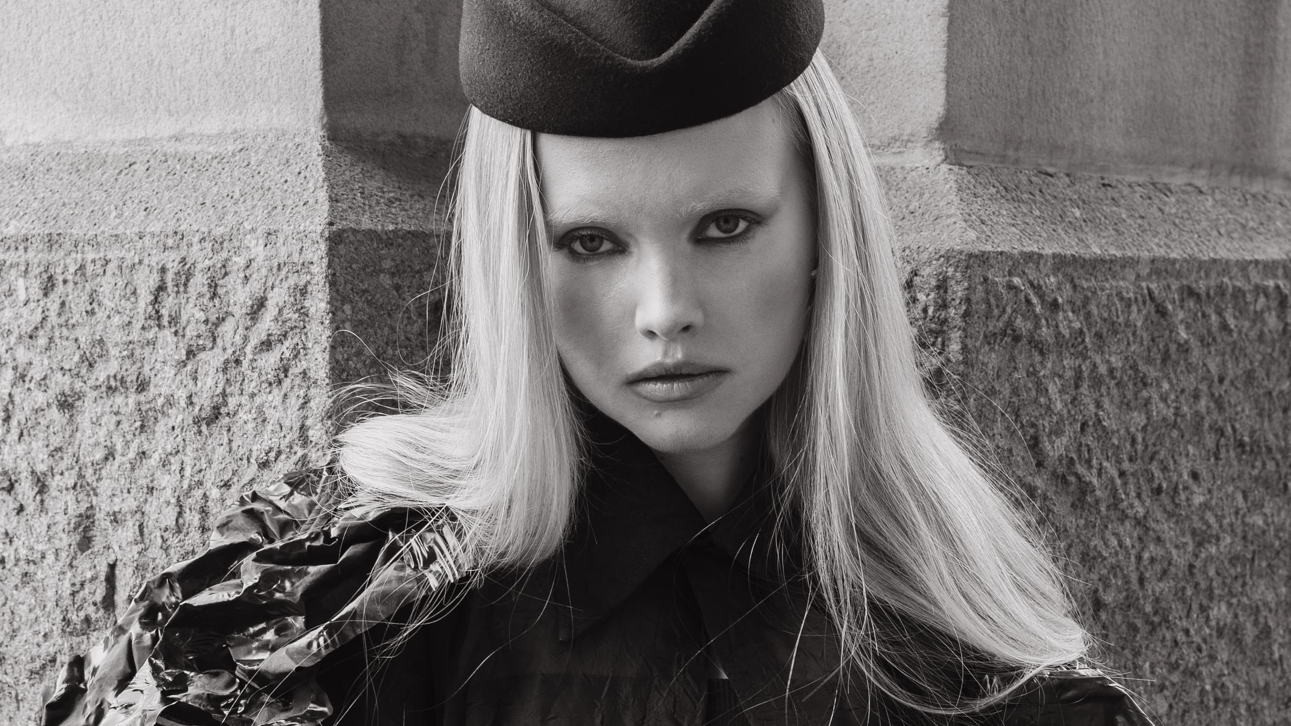 Black and white photo of a stylish woman in a chic outfit and hat.