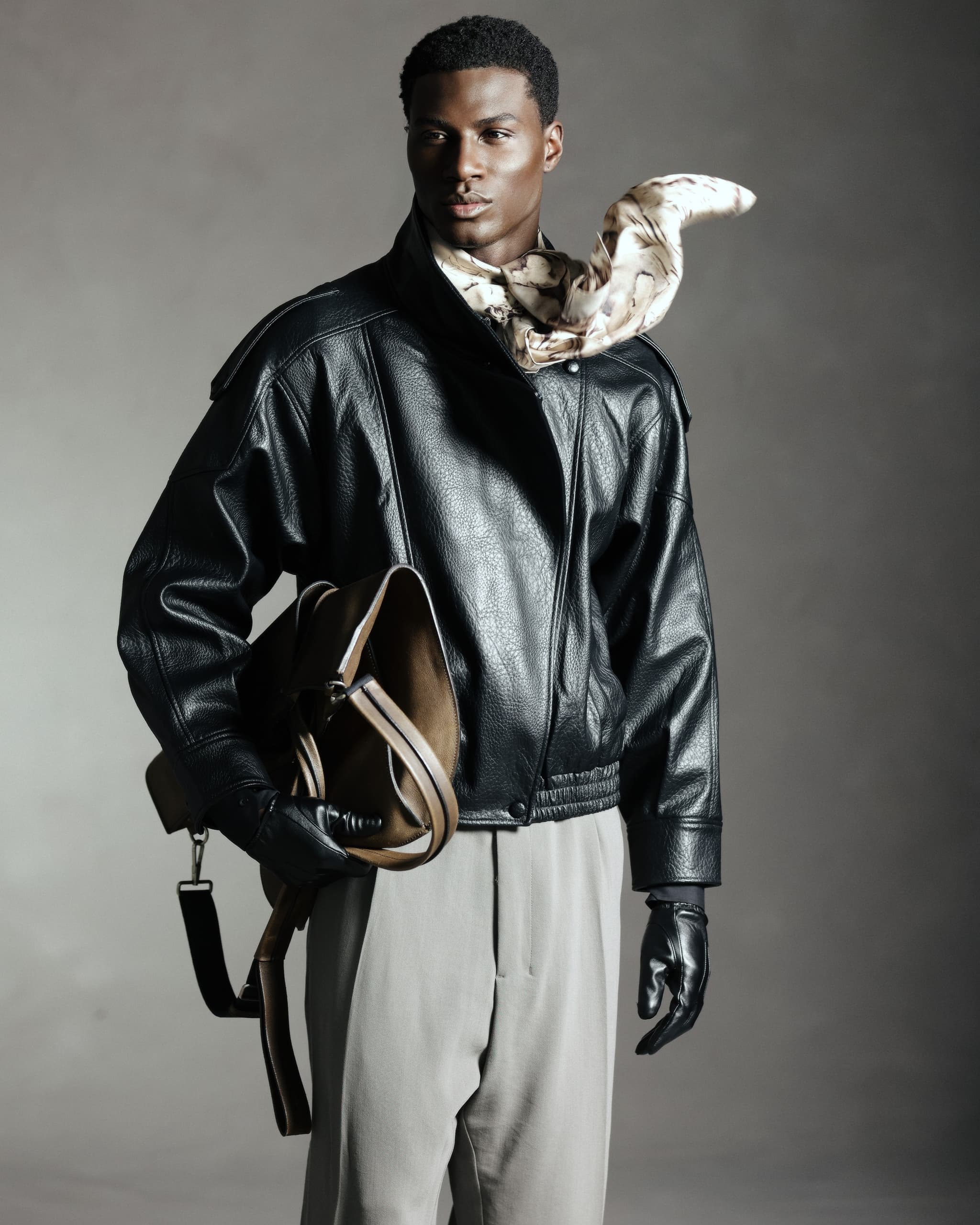 Model in leather jacket and gloves with scarf and bag, fashion portrait.