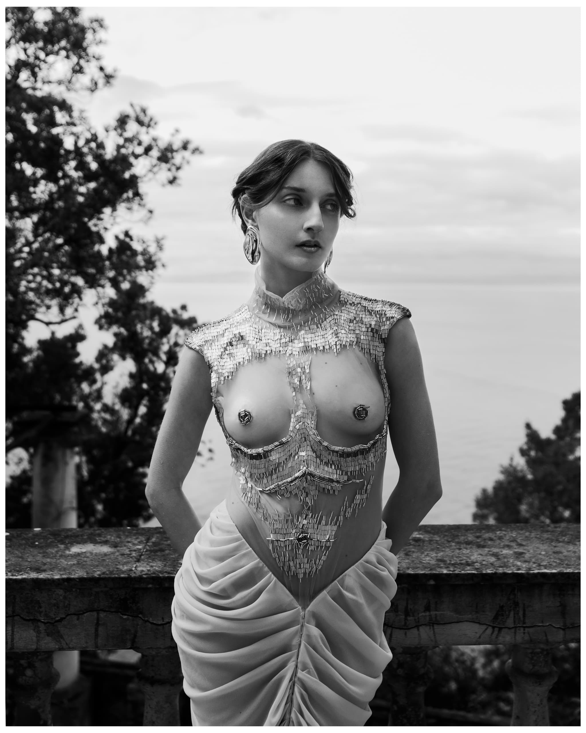 Fashion-forward artistic portrait with elegant, sheer, metallic dress design.