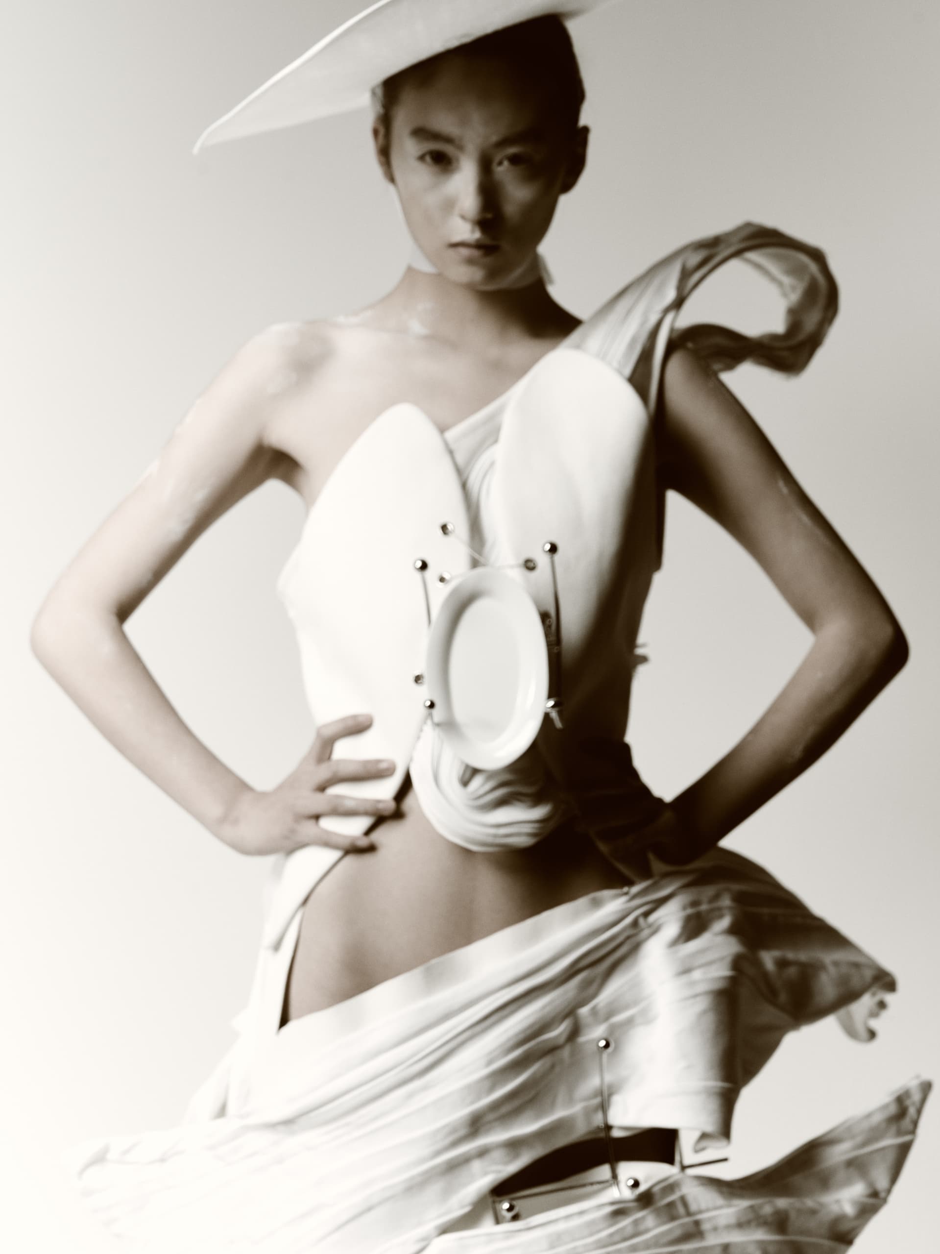 Avant-garde fashion model in artistic white dress and hat.