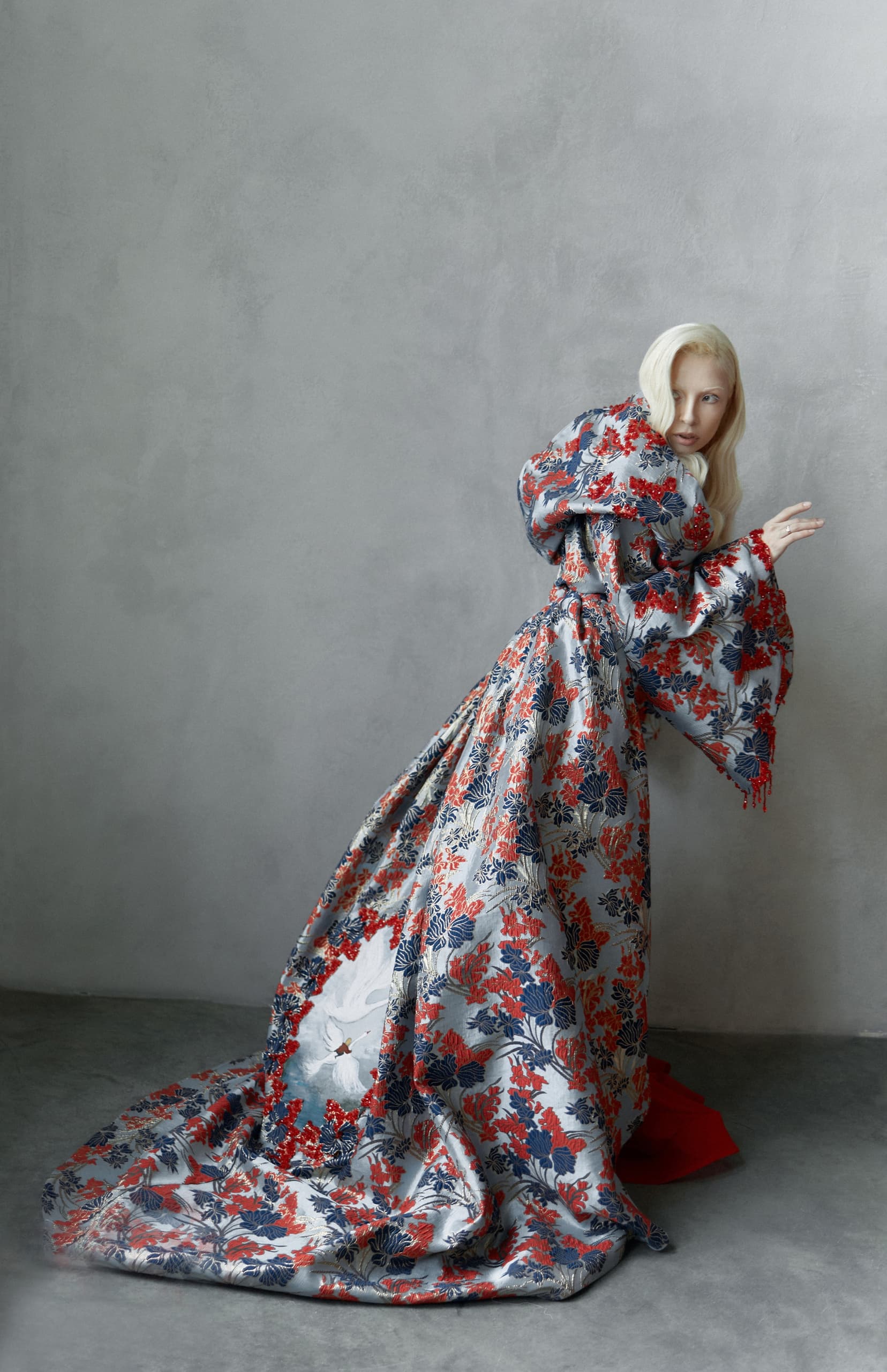 Model in a floral kimono poses against a gray backdrop.
