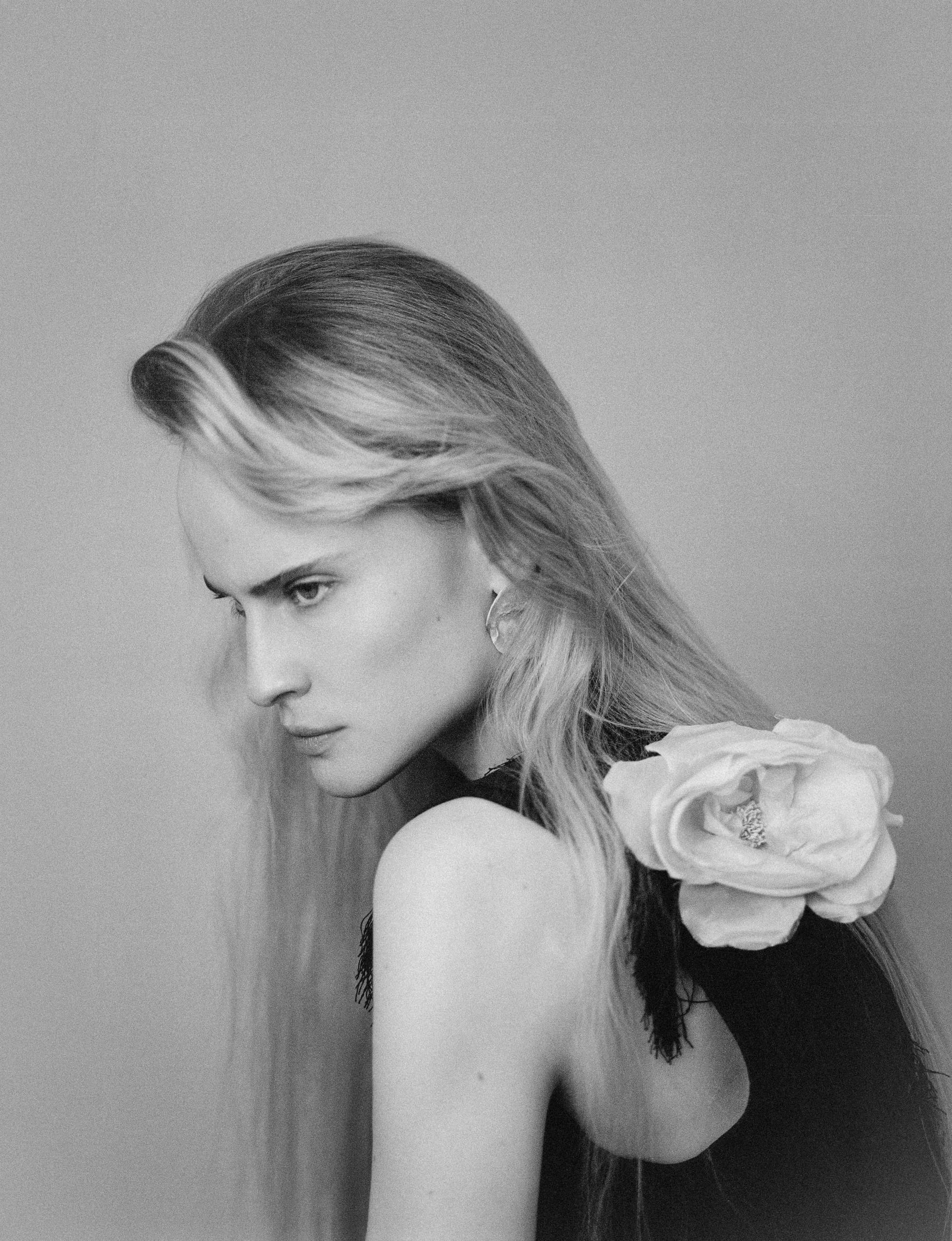 Black and white fashion portrait with floral shoulder accessory.