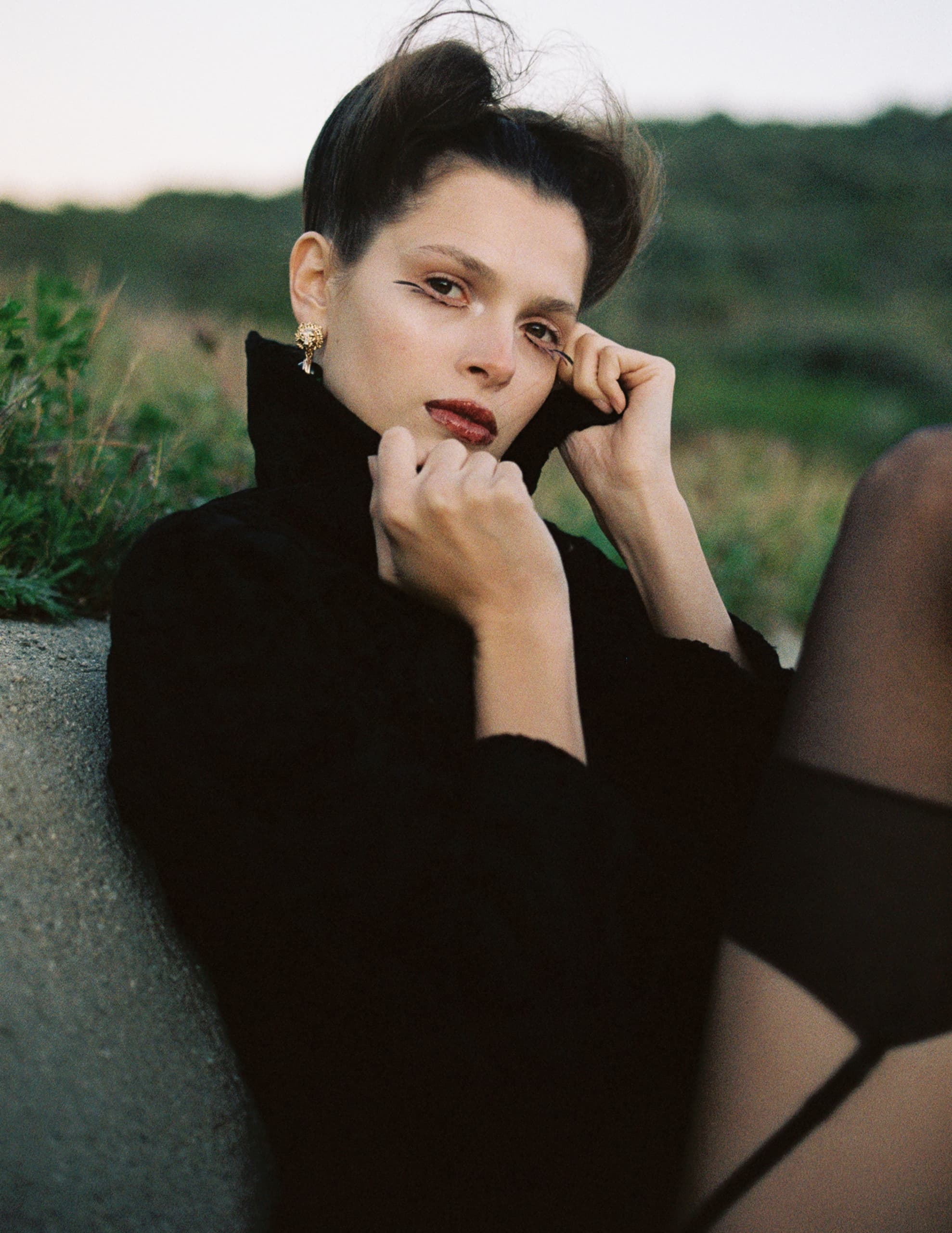 Fashionable woman outdoors in black coat, elegant pose.