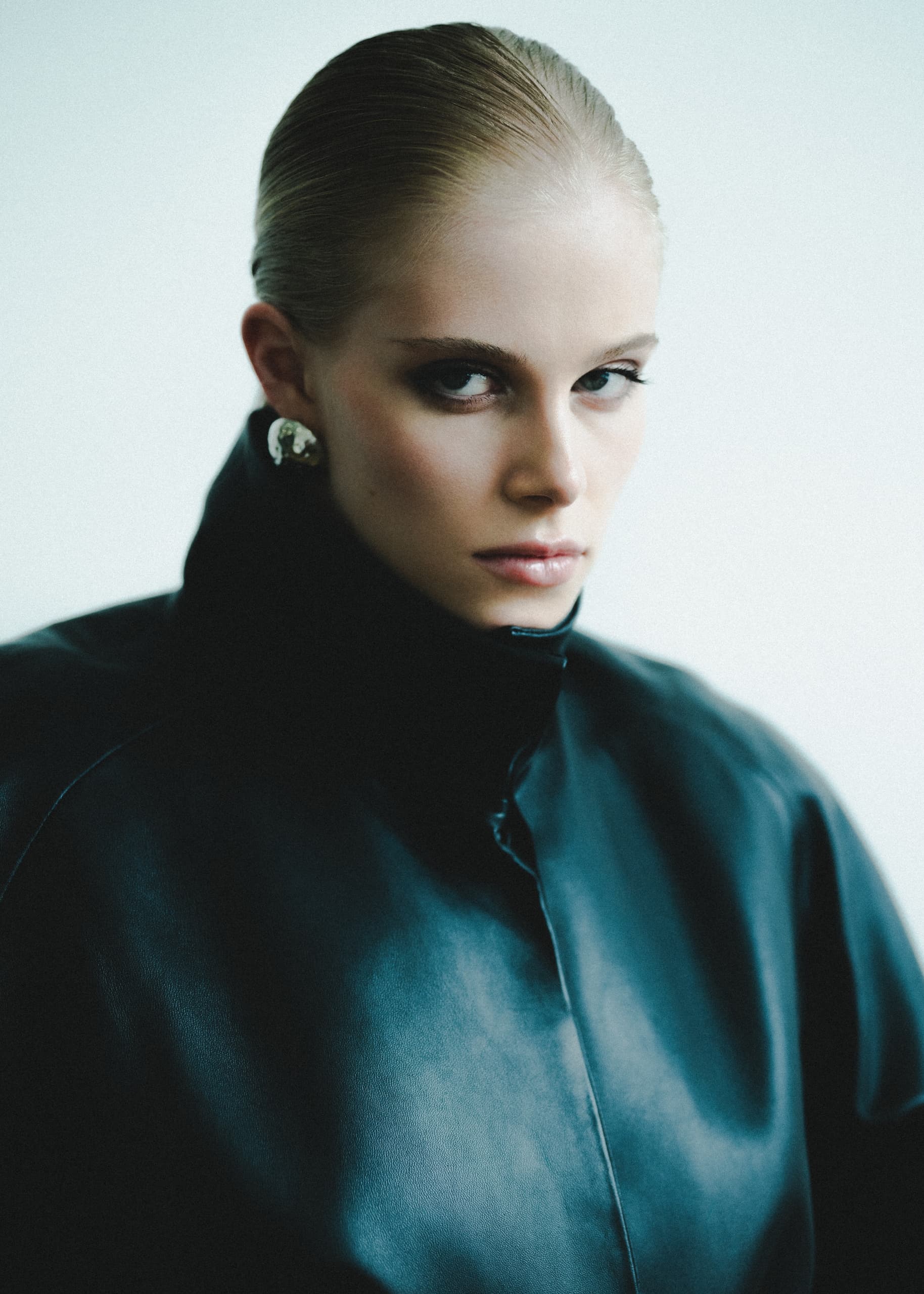 Fashion model in sleek leather jacket, intense gaze, modern style.