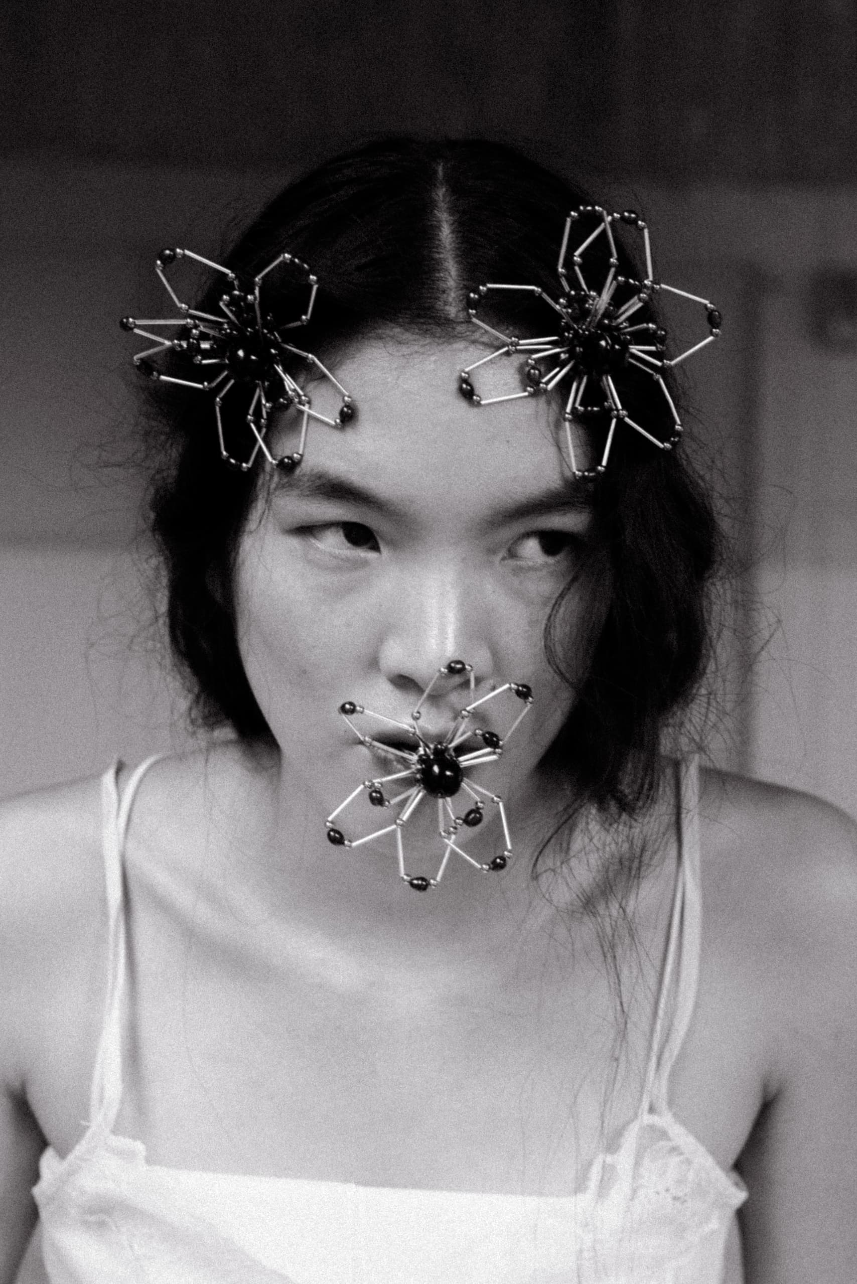 Avant-garde headpiece and lip fashion, flower-like wire design in monochrome.