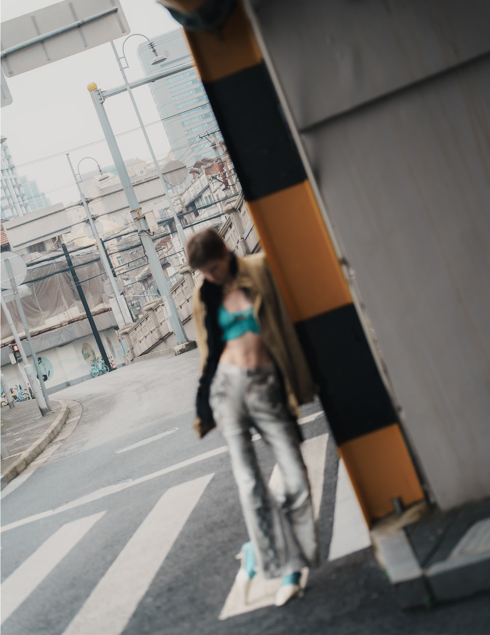 Stylish person leaning against wall in urban street setting.